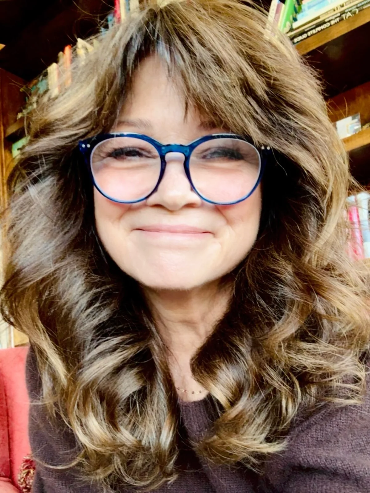 Woman over 50 with a voluminous wavy brown blowout with big soft volume.