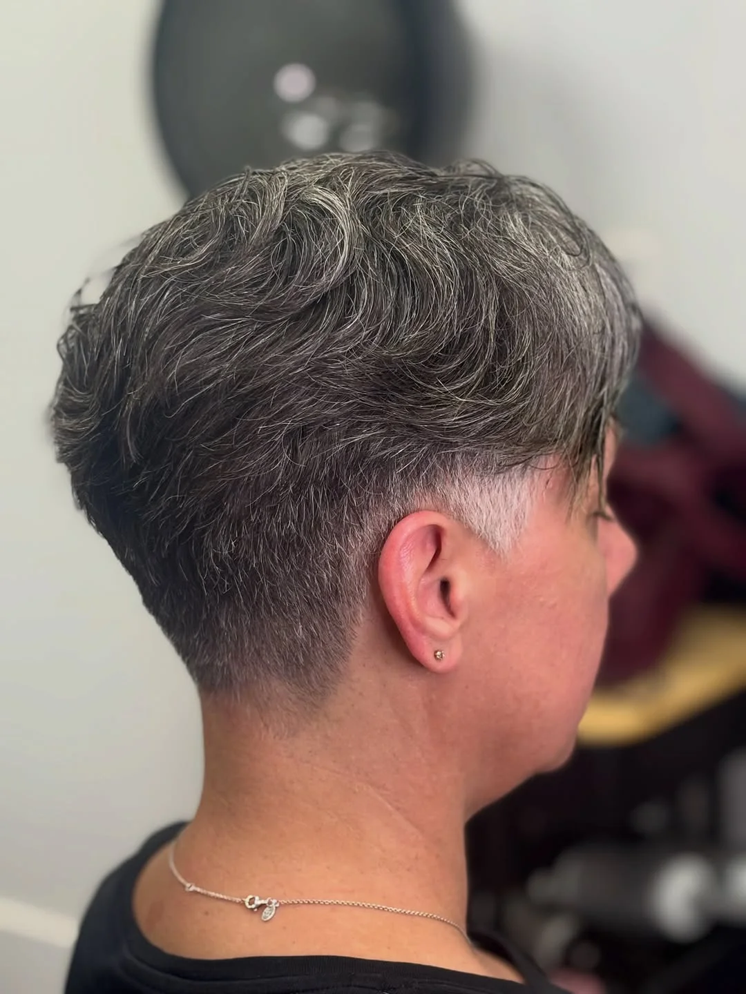 Woman with an edgy pixie featuring a closely buzzed nape and longer crown