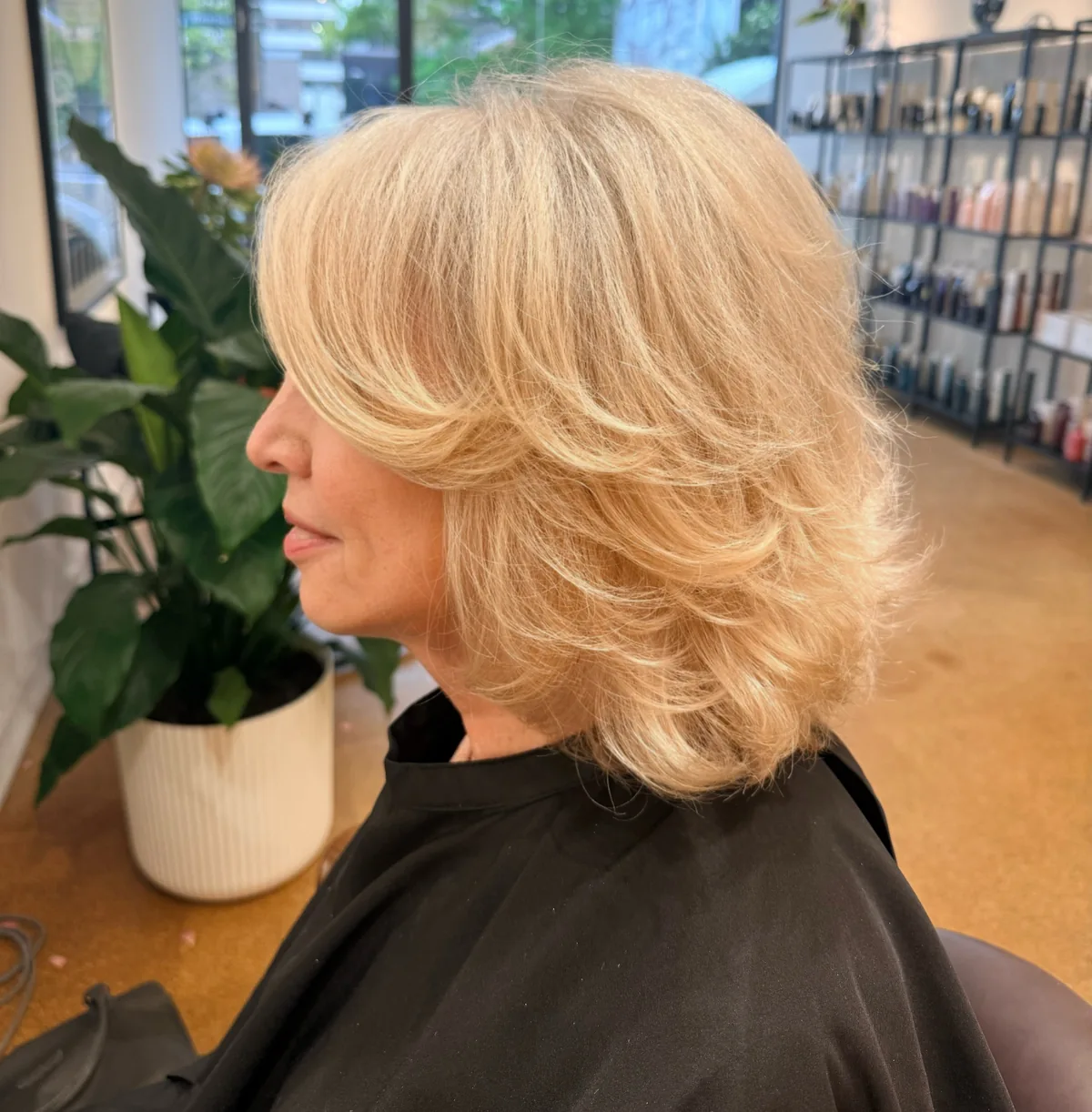Woman over 50 with fine blonde hair wearing feathered layers with a side part
