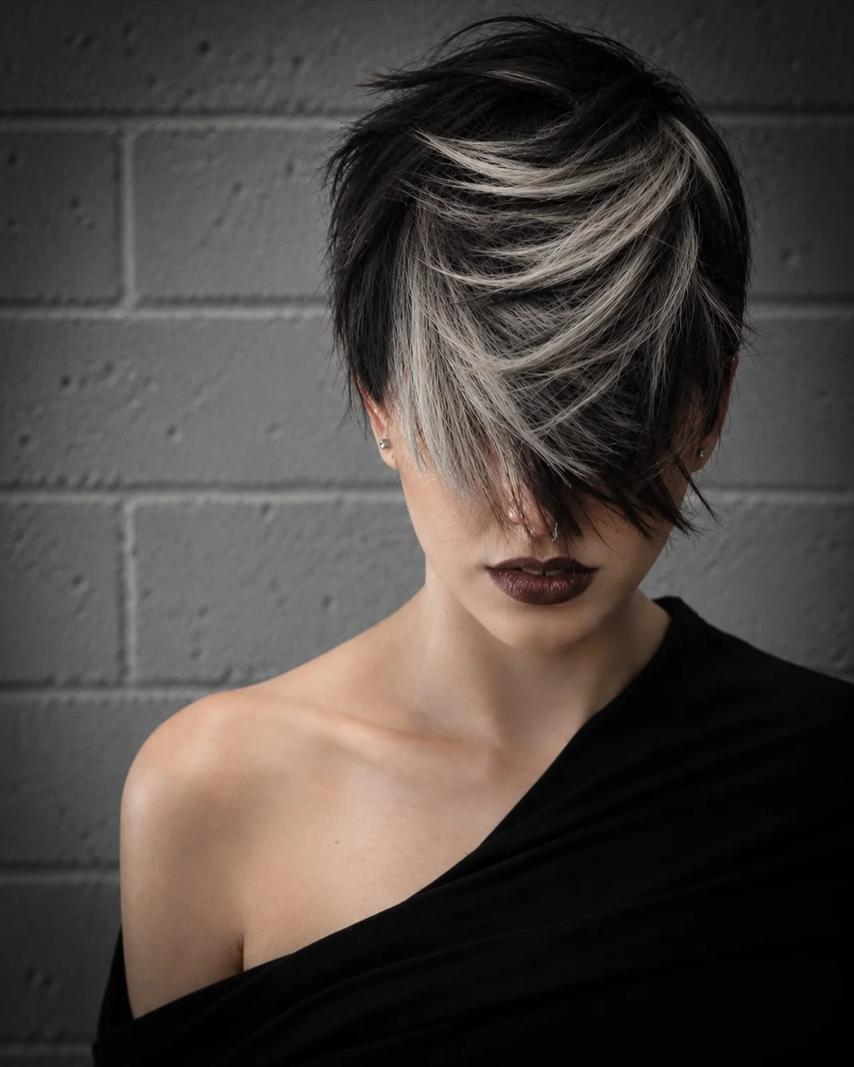 Woman with an edgy long pixie styled with a deep side part and swept-over fringe