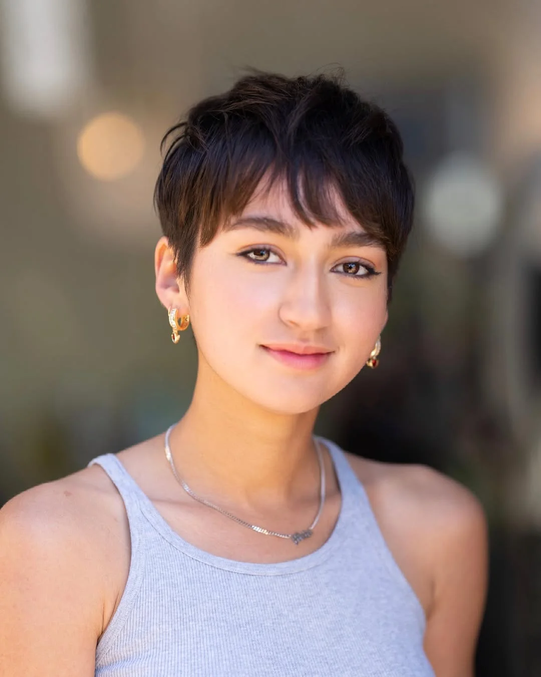 Woman with an edgy pixie featuring choppy, textured bangs across the forehead