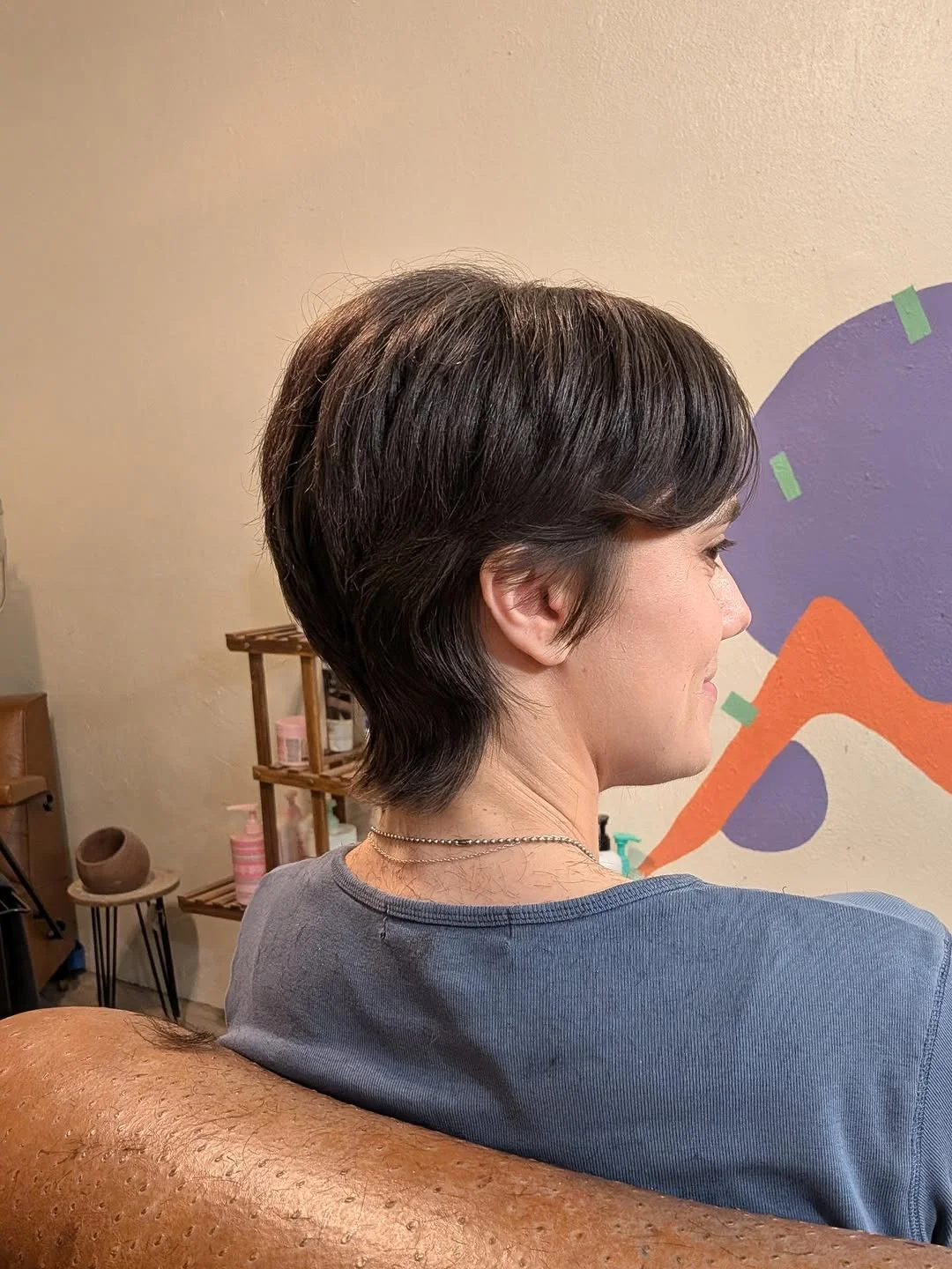 Woman with an edgy pixie featuring a short crown and unexpectedly longer nape