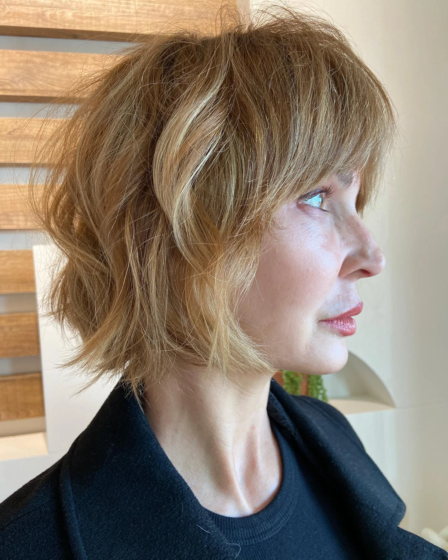Woman with thin fine hair wearing a shaggy bob styled with deliberately tousled, undone texture