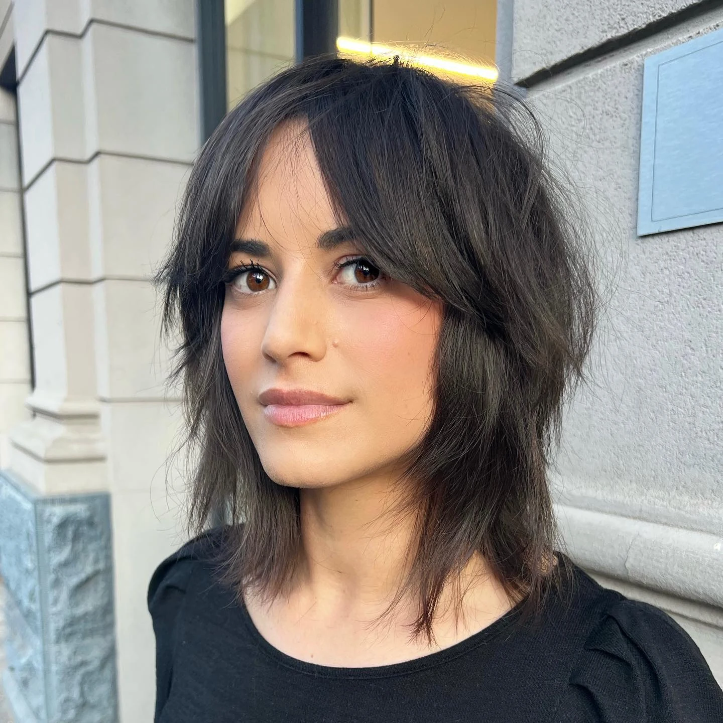 Woman with thin fine hair wearing a shaggy wolf-cut bob with heavy layering