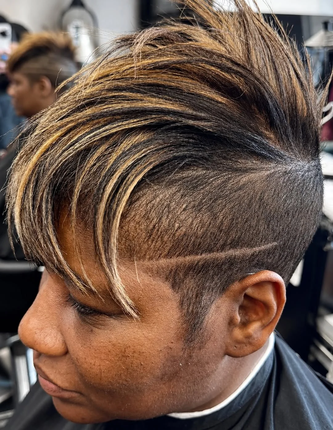 Woman with an edgy side-swept pixie featuring a hidden undercut beneath