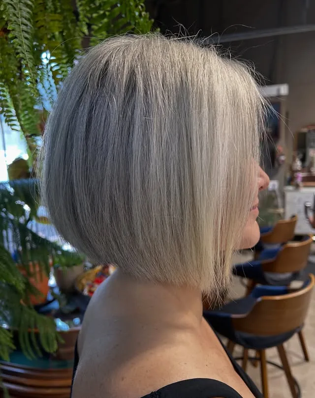 Woman over 50 with grey hair wearing a sleek chin-length blunt bob with gently rounded ends