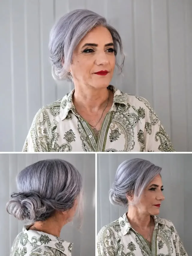 Woman over 50 with silver-grey hair in a soft textured low updo with loose face-framing pieces