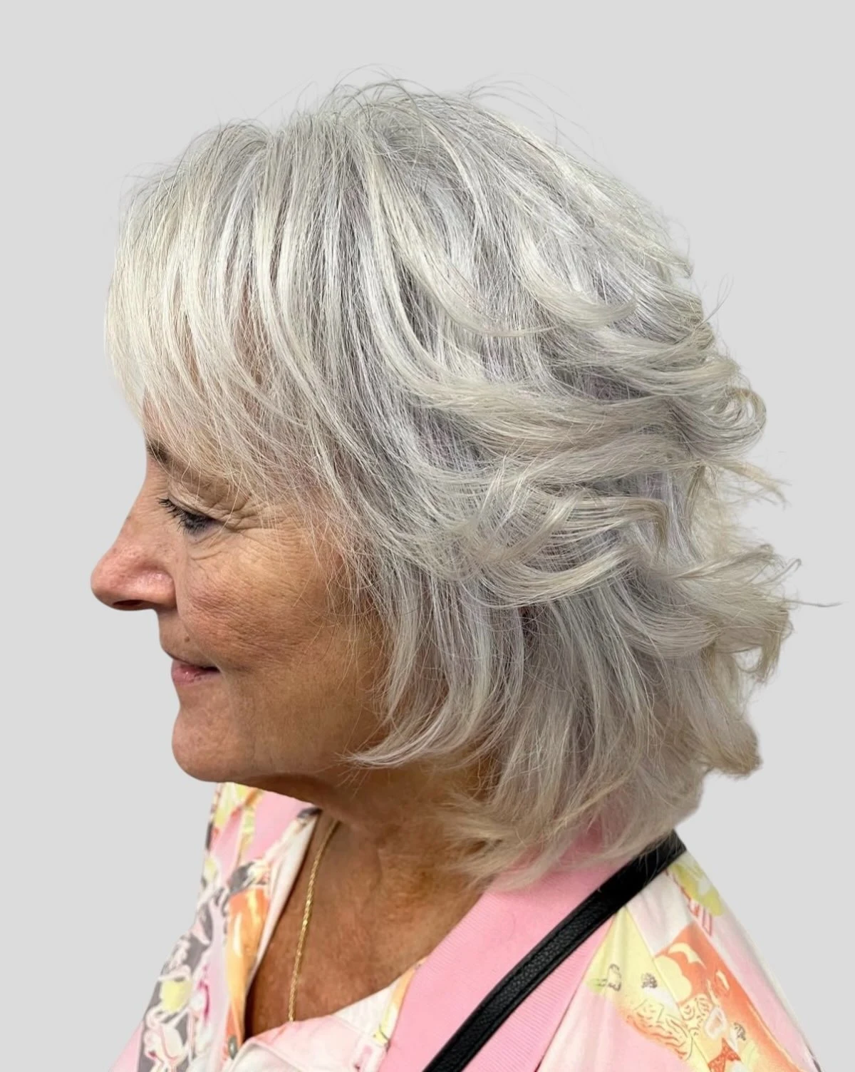 Woman over 60 applying texturizing spray to a bob hairstyle for effortless texture