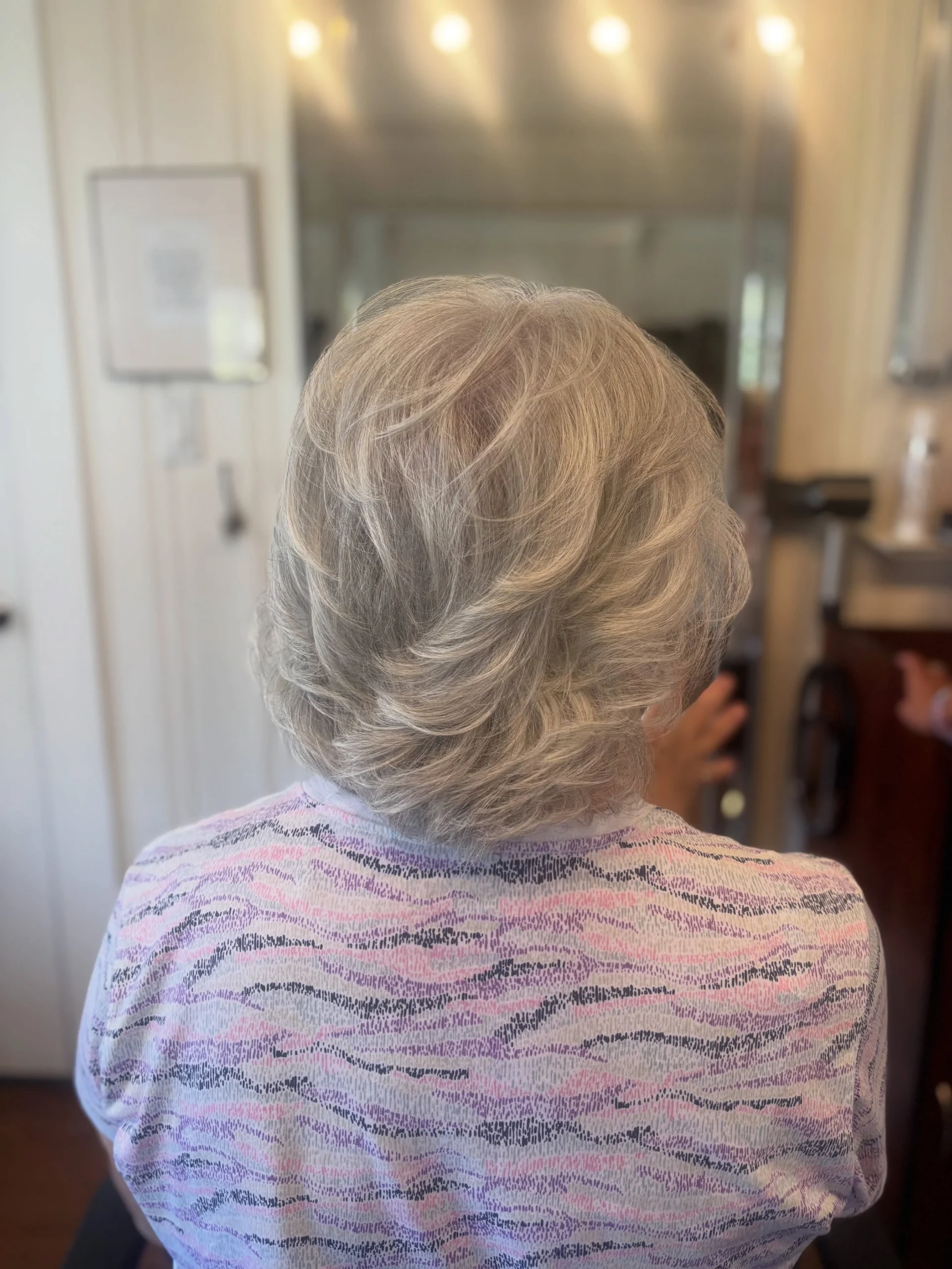 Woman over 60 getting a voluminous round-brush blowout on a bob hairstyle