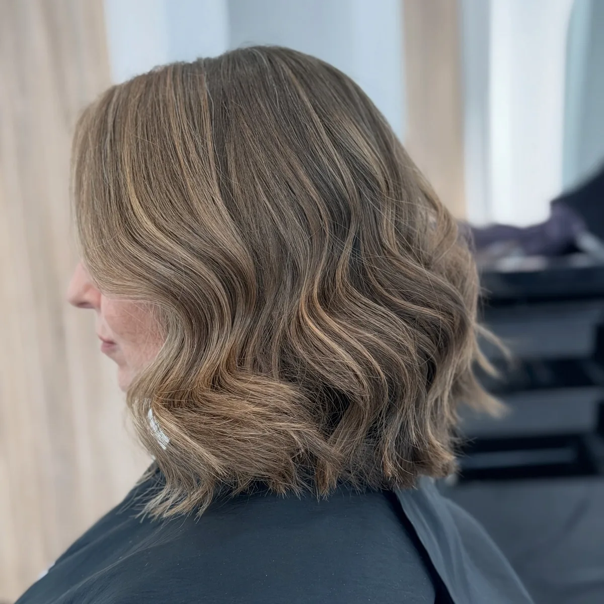 Woman at 60 with a wavy shoulder-length lob and soft layers