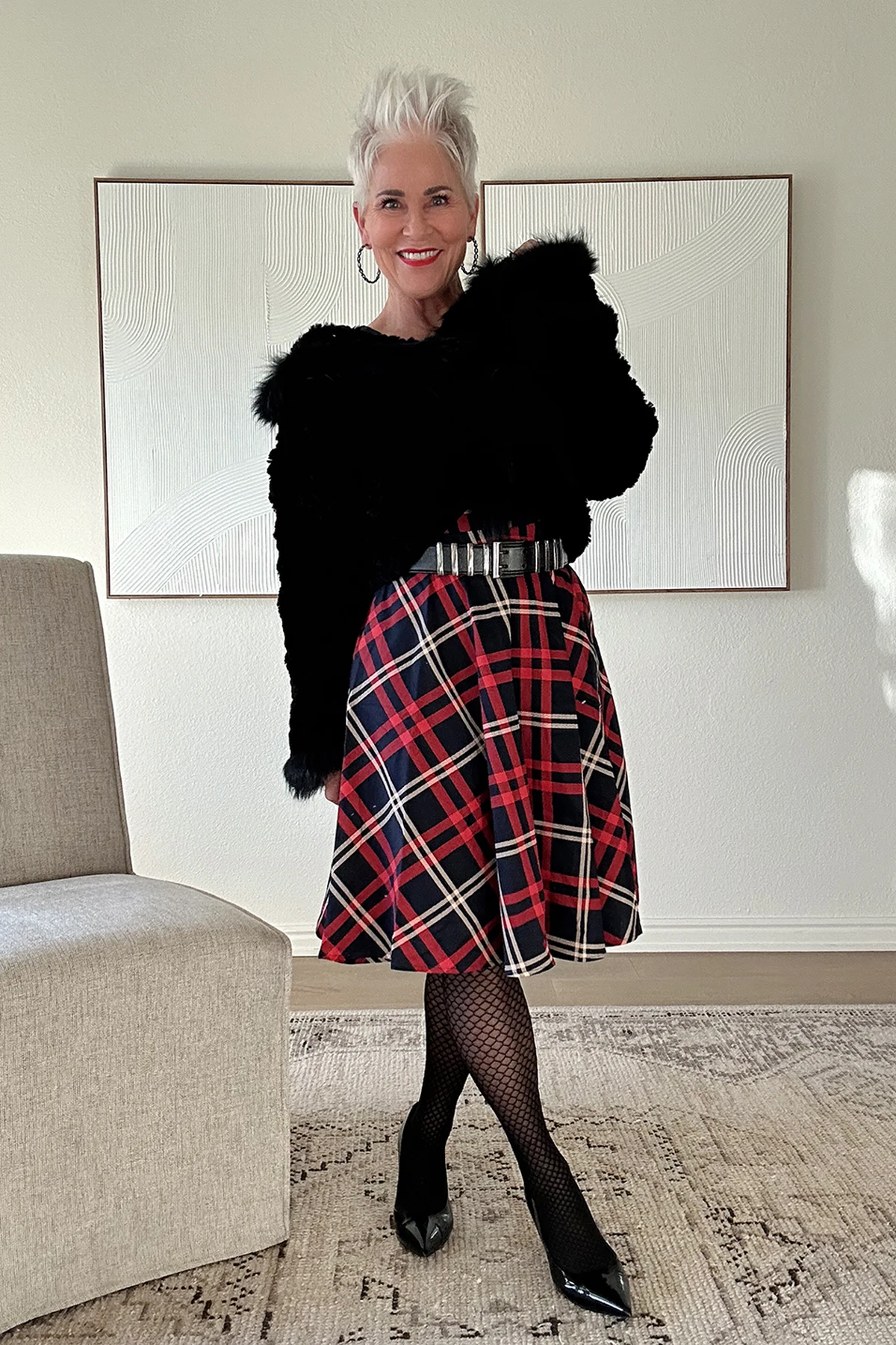 A woman over 50 wears a plaid A-line midi dress with a cropped faux-fur jacket and wide belt.