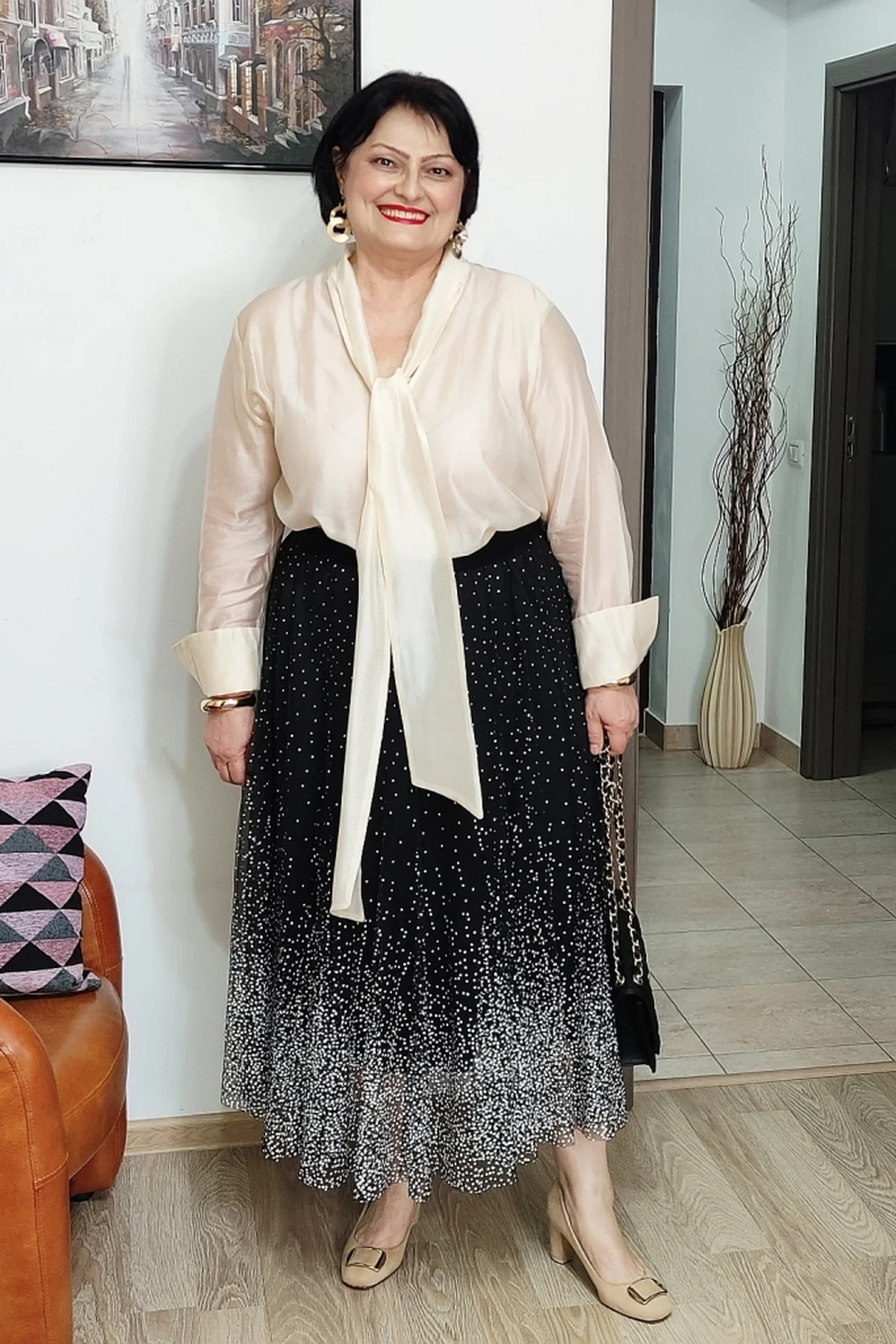 Woman in an ivory silk blouse and black sparkly midi skirt at home at Christmas