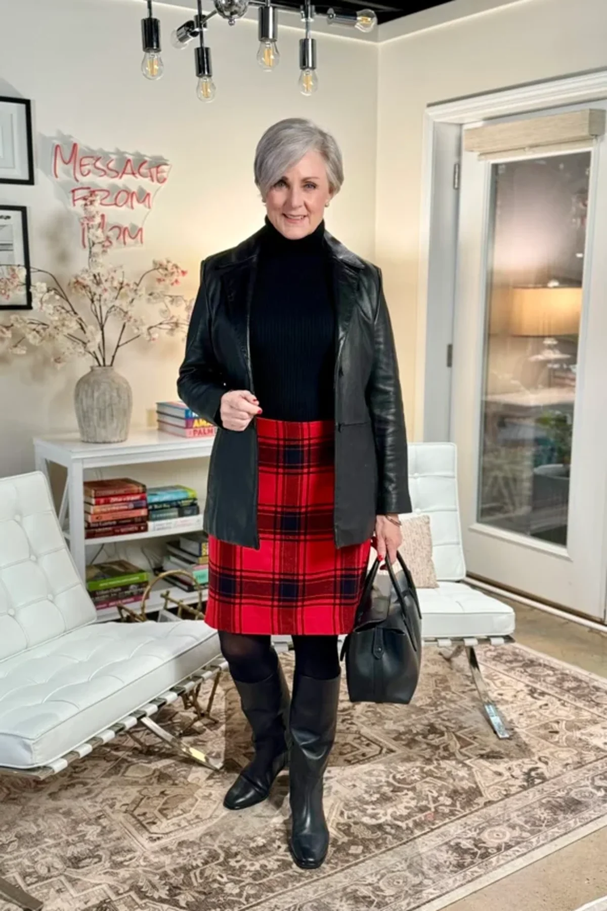 Woman in a black turtleneck, tartan midi skirt and knee boots