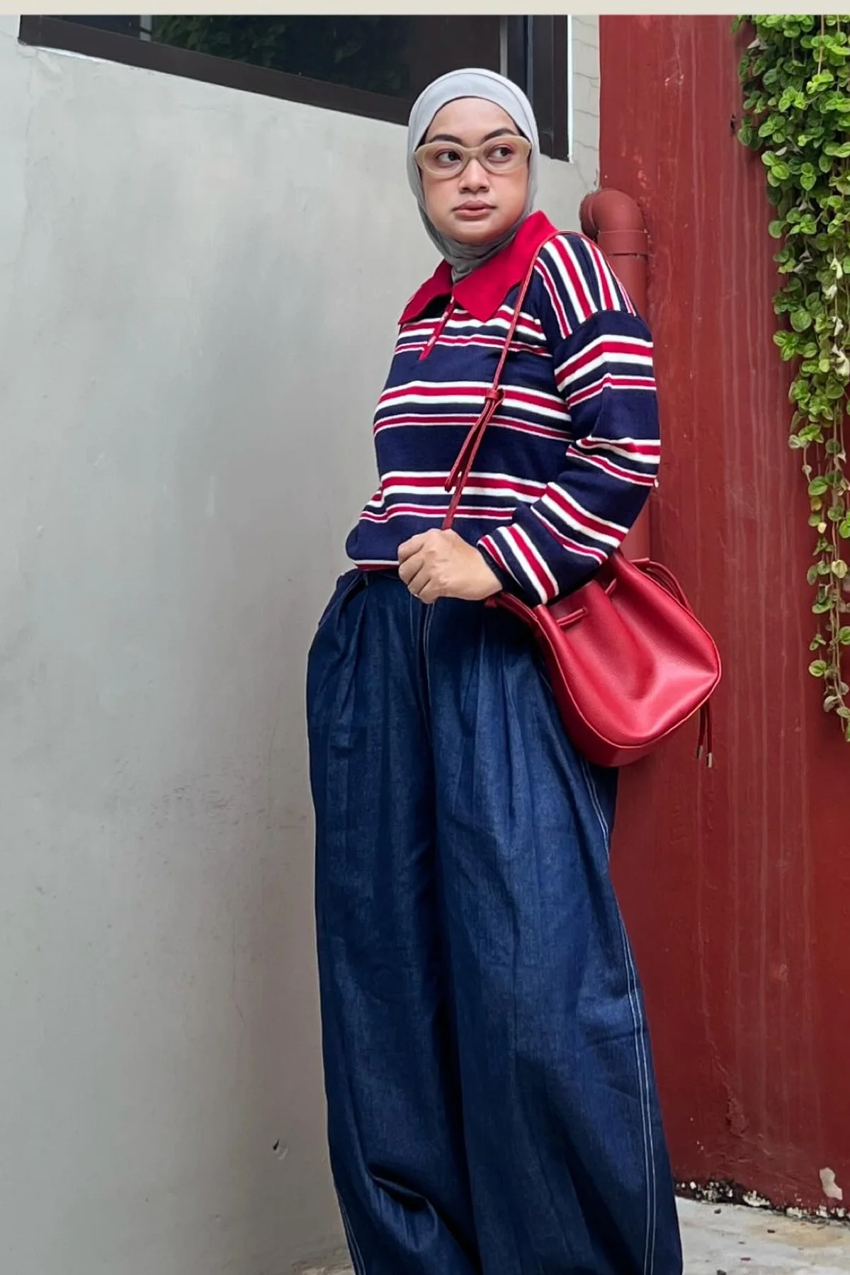 Hijabi woman in striped navy sweater, navy trousers and red hijab shopping at Christmas