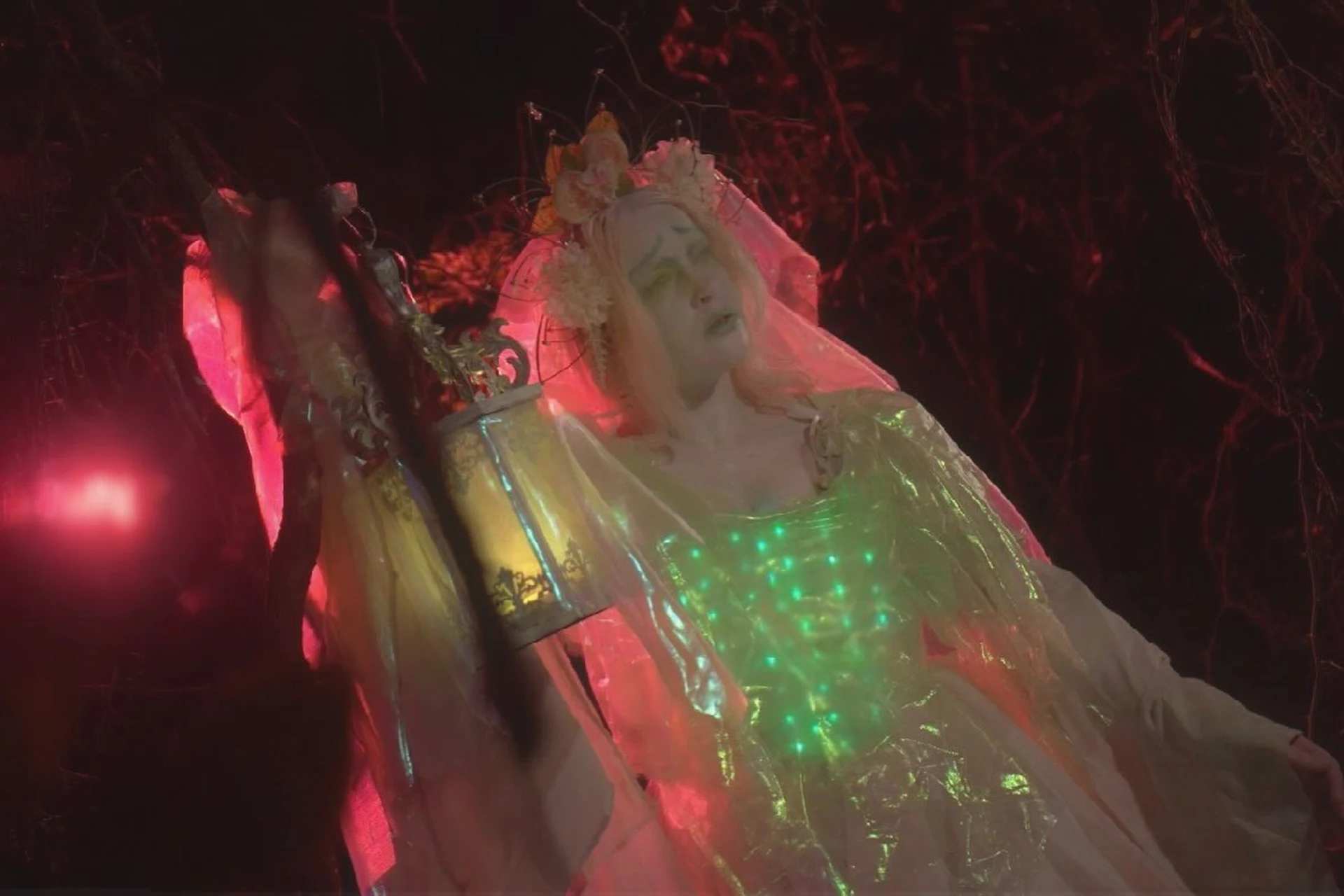 Woman in a DIY ghost bride costume with veil holding a glowing lantern at night, a last minute creepy Halloween costume idea