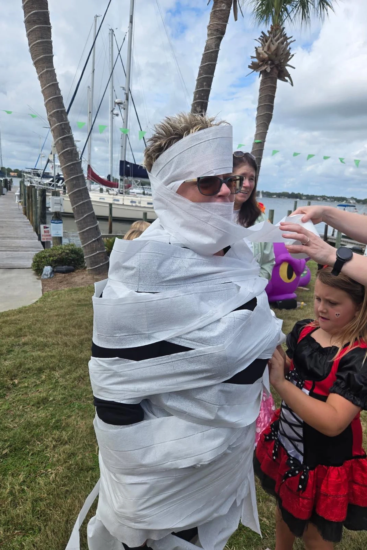 Woman over 50 wrapped in toilet paper over a cream knit, a DIY mummy Halloween costume