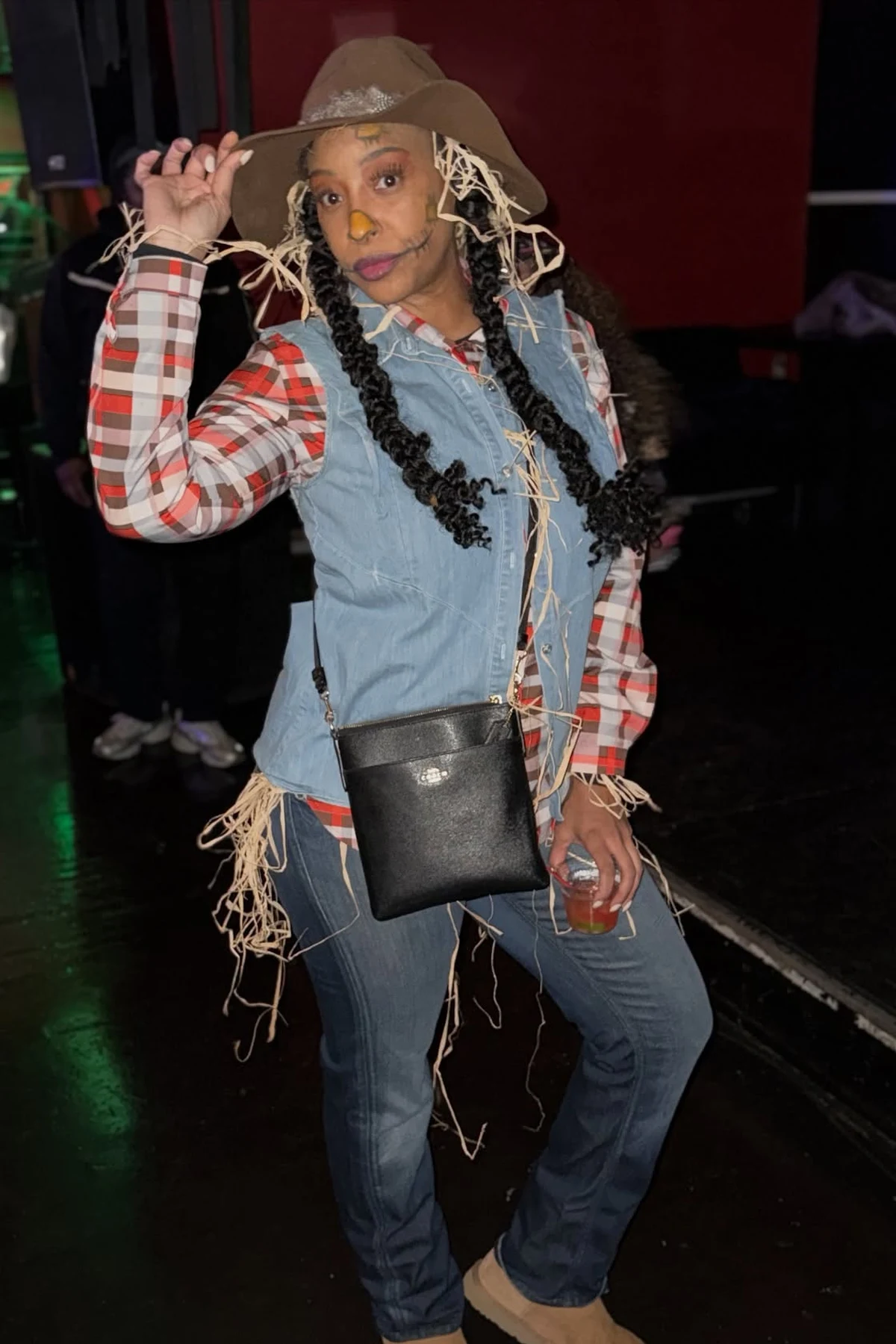 Woman over 50 in a flannel shirt and jeans with straw and a painted scarecrow smile, a DIY scarecrow Halloween costume