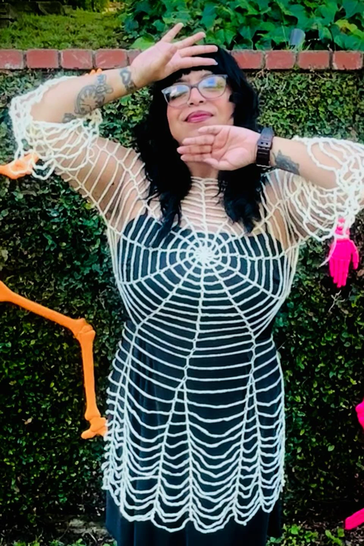 Woman over 50 in a black dress draped with fake spider webs, a DIY spider lady Halloween costume