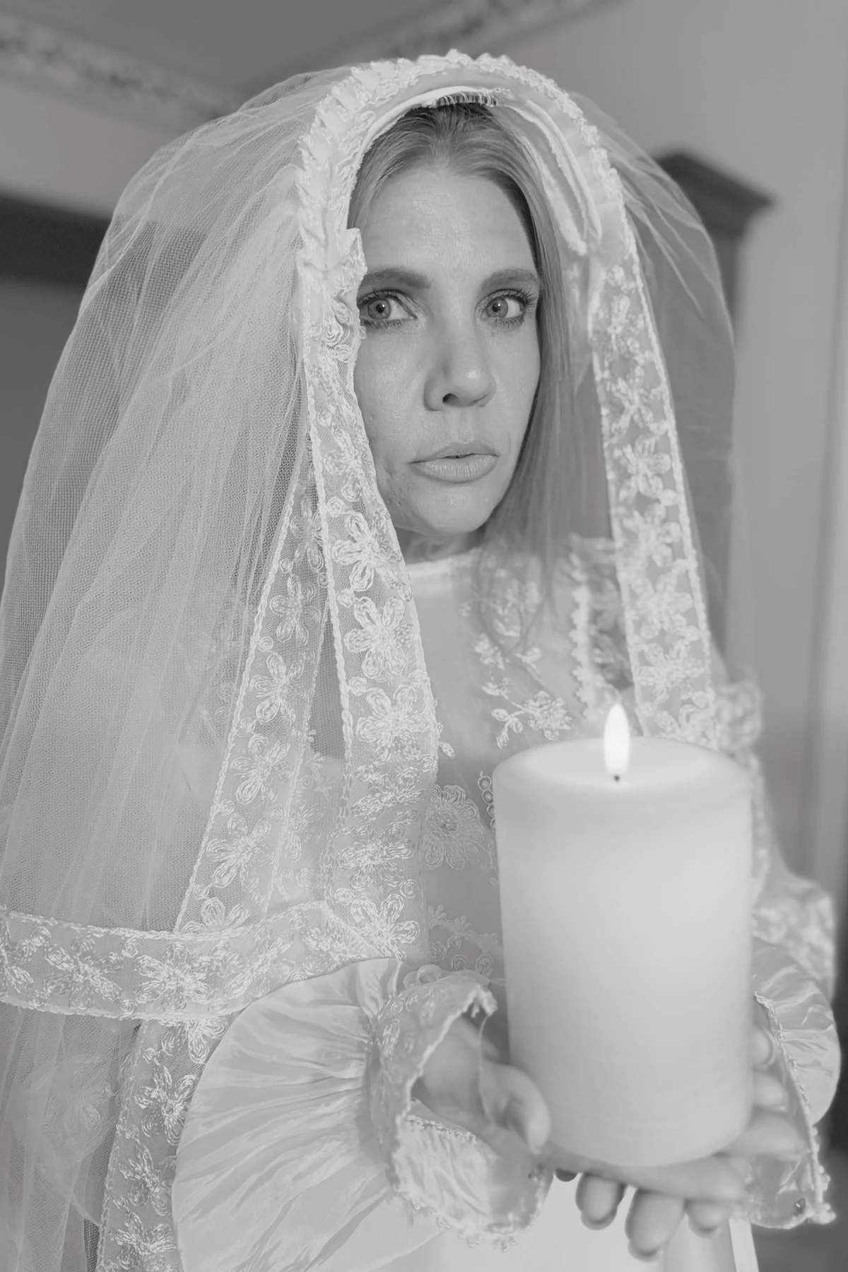 Woman over 50 in a torn white dress and veil, a DIY ghost bride Halloween costume