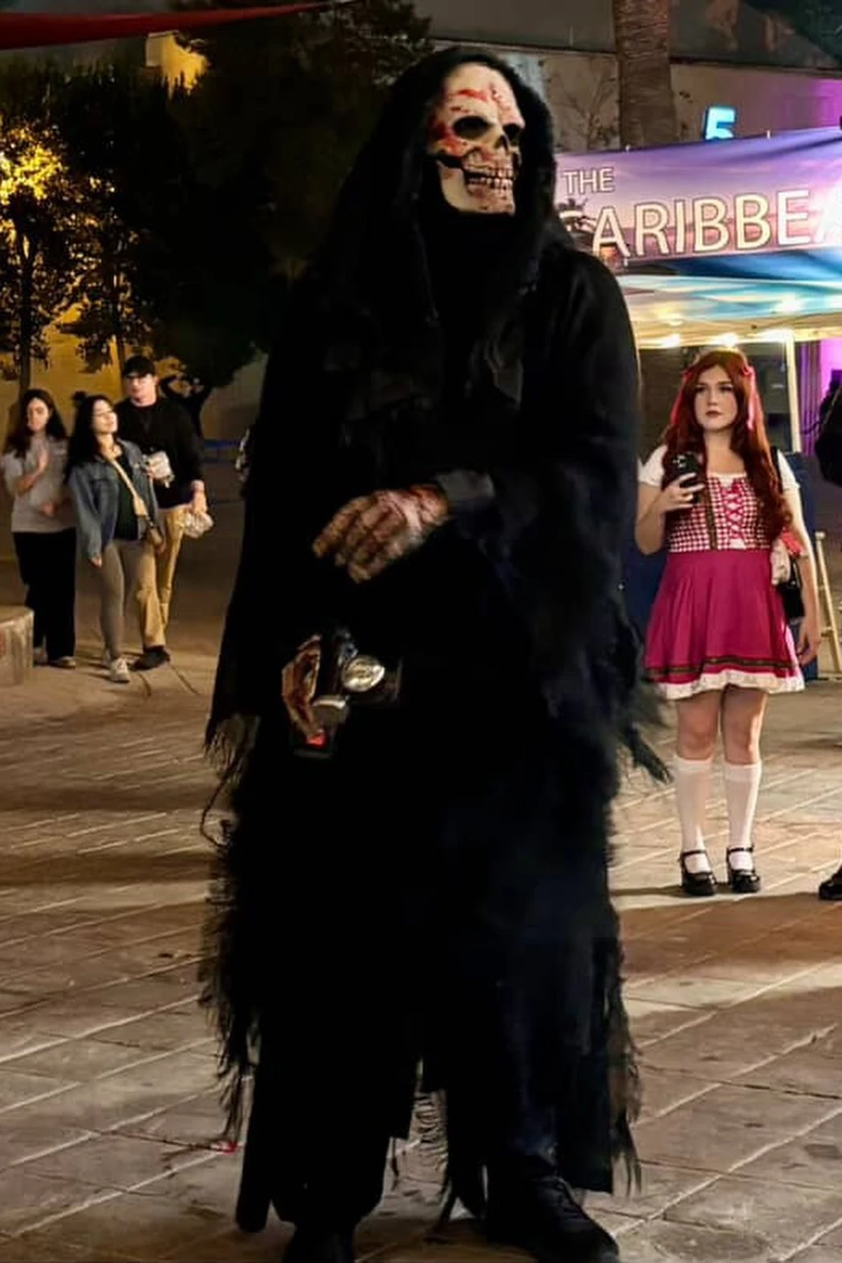 Person dressed as the grim reaper in a black hooded cloak and skull mask, a DIY grim reaper Halloween costume