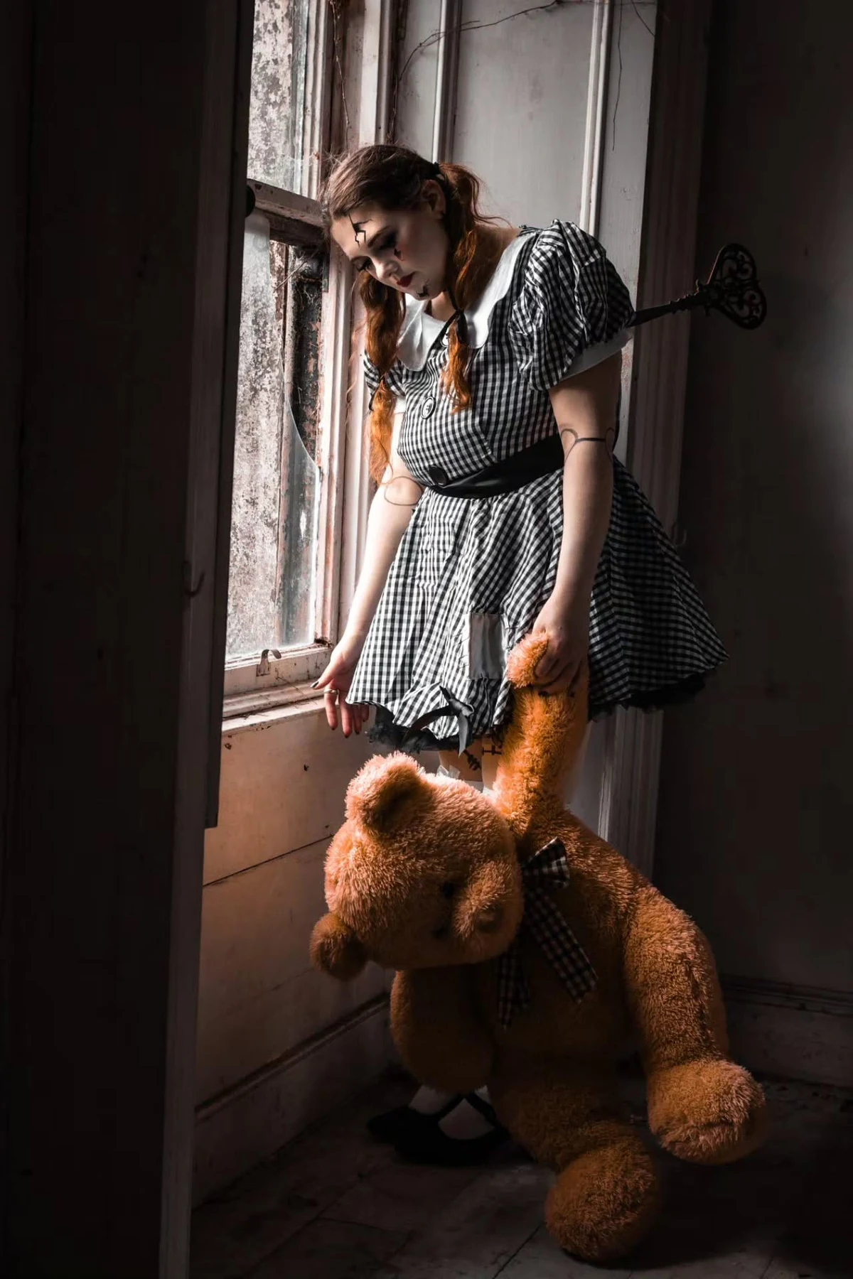 Woman over 50 in pajamas with dark creepy eyes holding a doll, a DIY possessed child Halloween costume