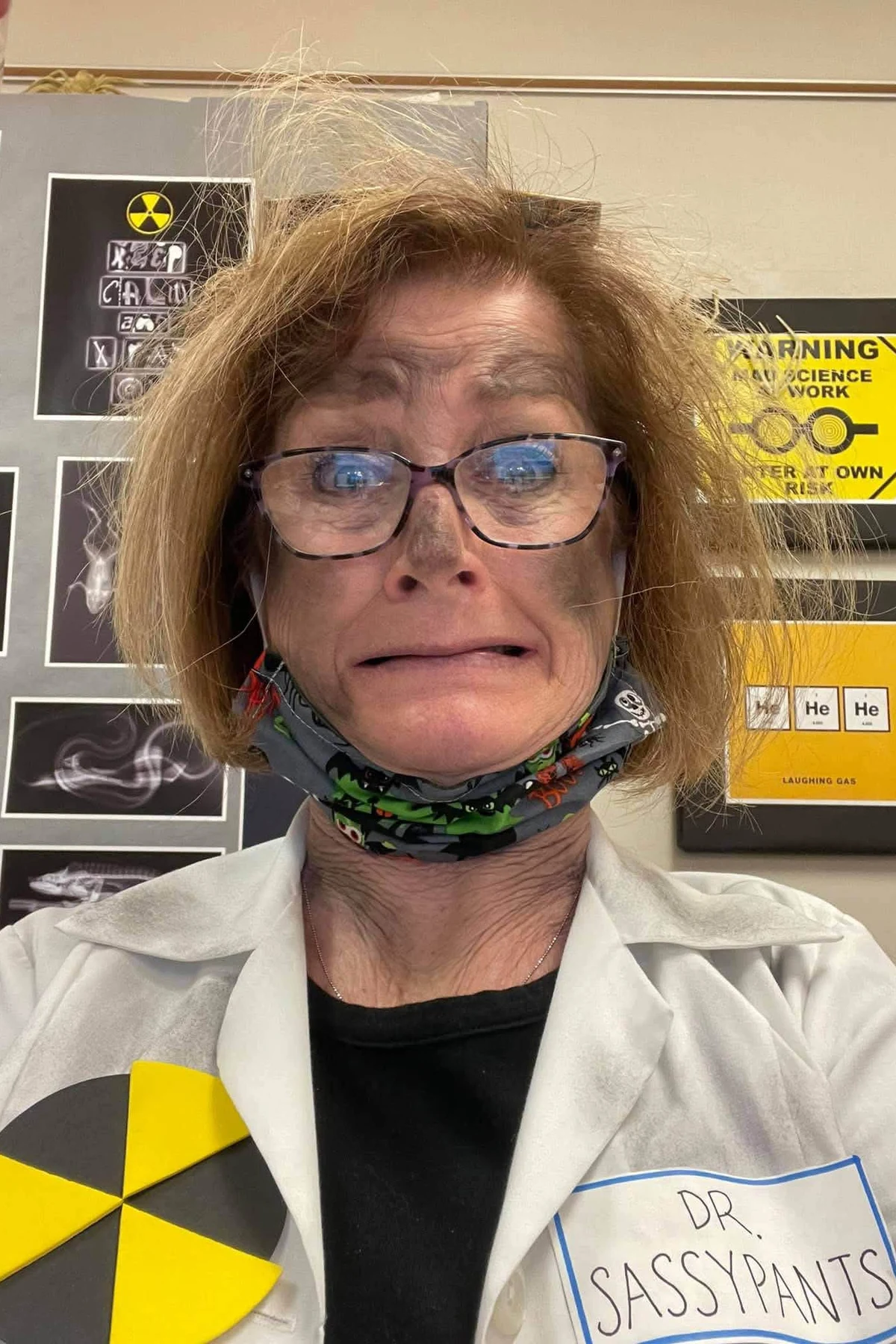 Woman over 50 in a white lab coat with wild hair, a DIY mad scientist Halloween costume