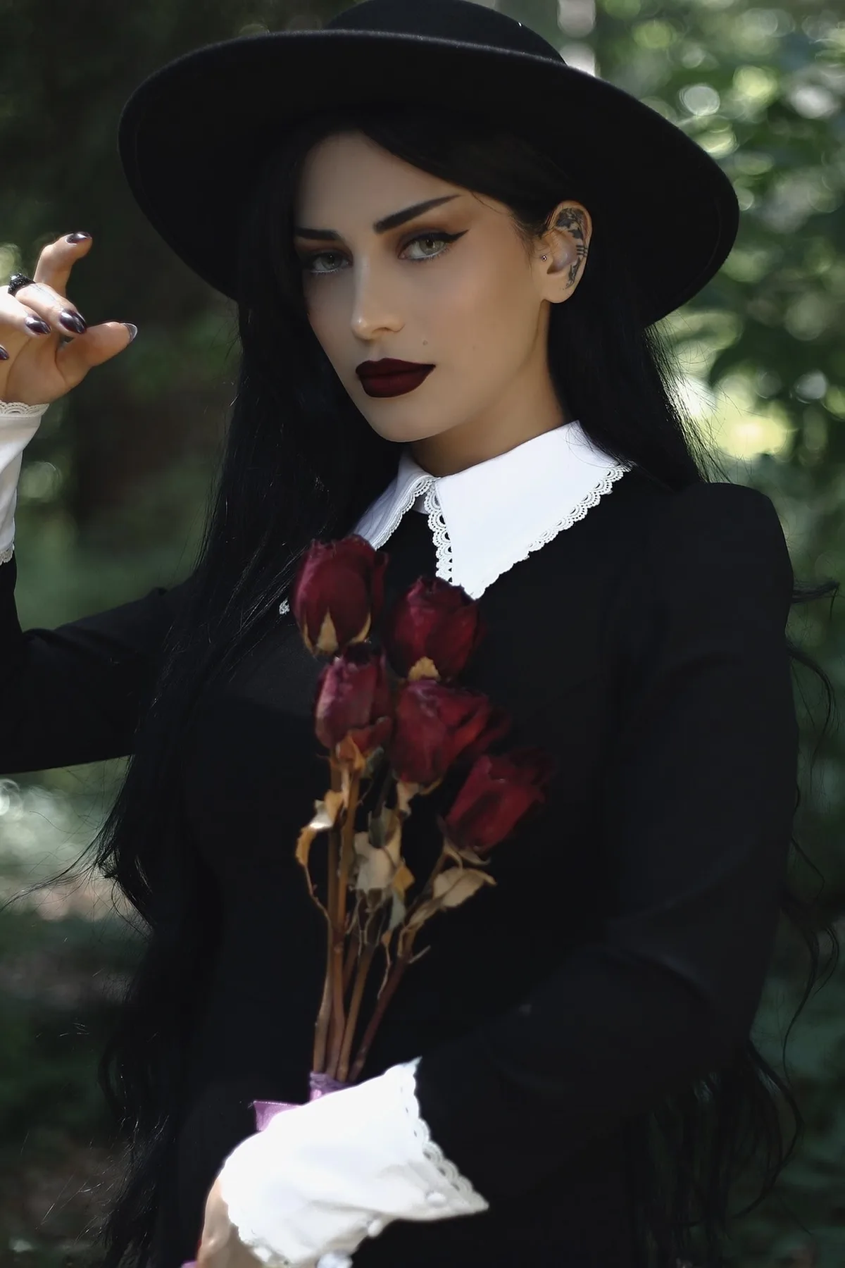 Woman over 50 in an all-black midi dress and wide-brim hat, a mysterious gothic stranger Halloween costume.