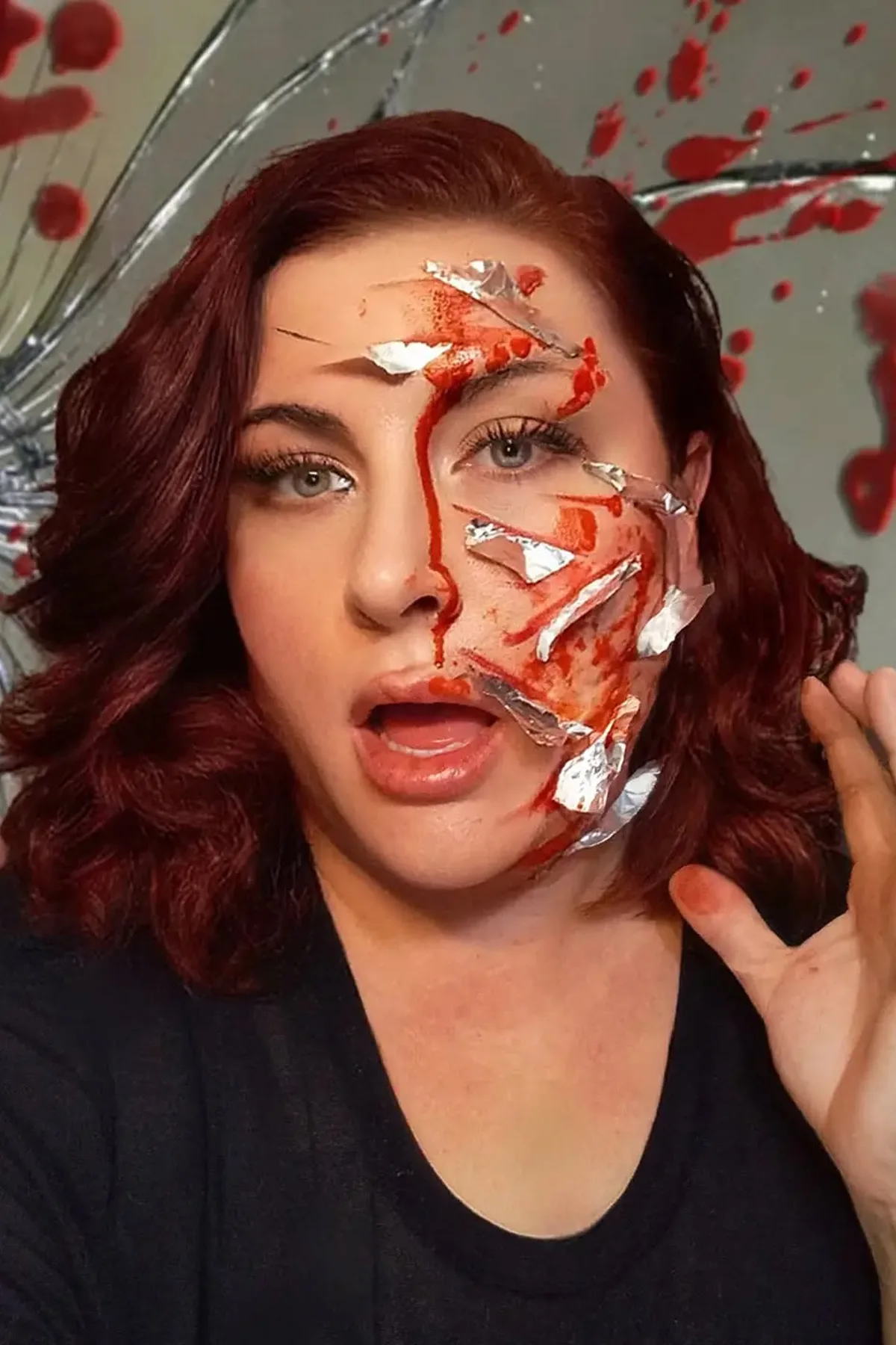 Woman in her 50s in a silver gown with mirror shards and cracked-mirror face paint, a haunted mirror ghost solo horror Halloween costume