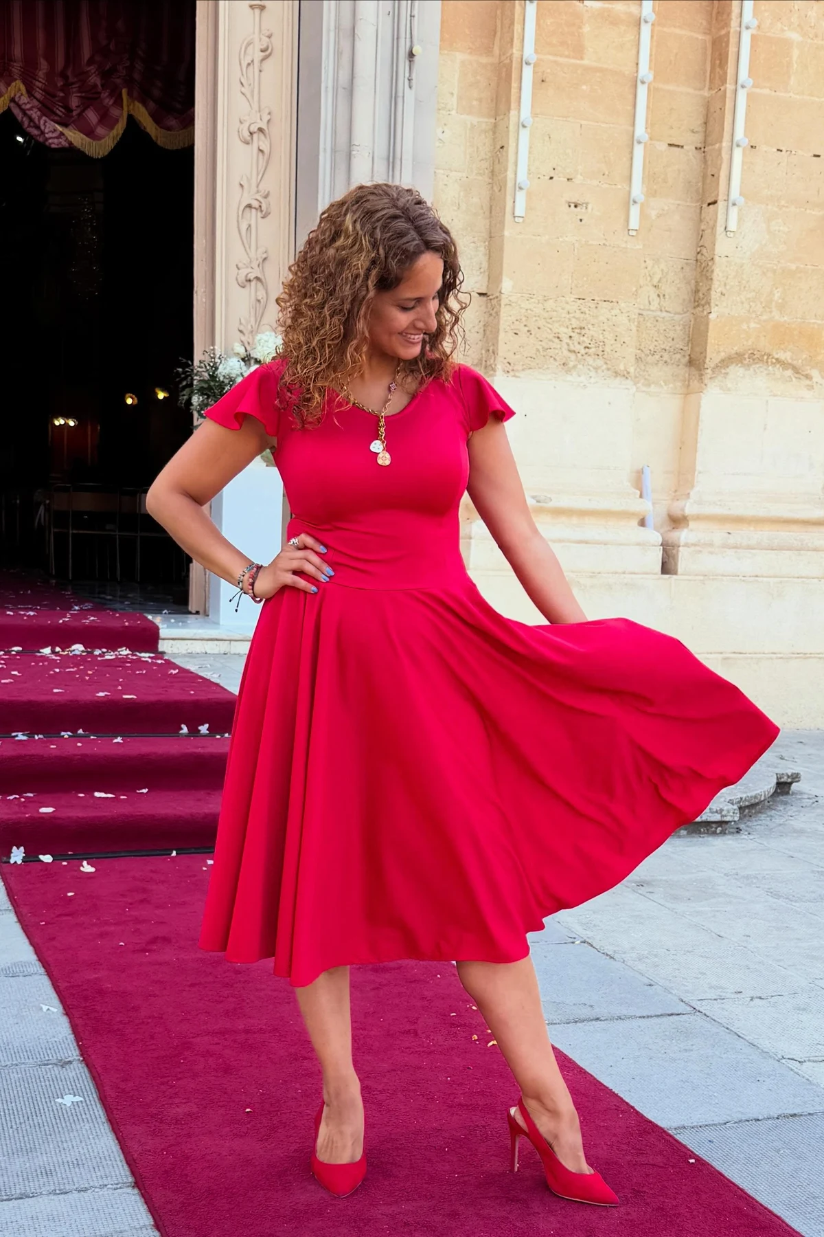 Woman in red fit-and-flare midi dress and red heels at a church entrance at Christmas