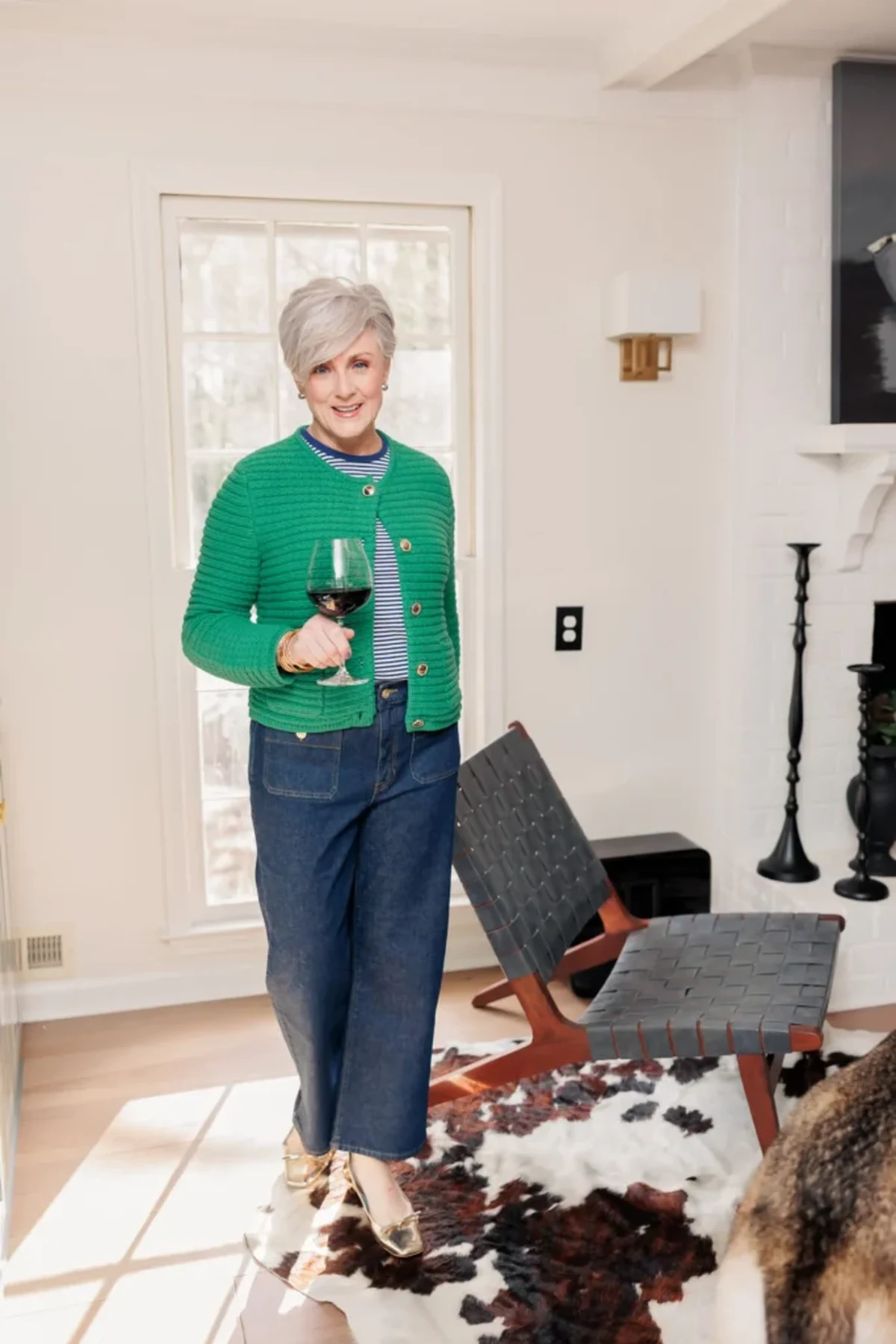 Woman in green cardigan and dark wide-leg jeans in a living room at Christmas