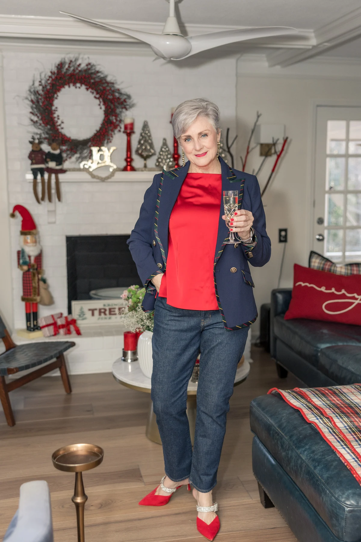 Woman in navy blazer with tartan trim and red satin top in a Christmas living room