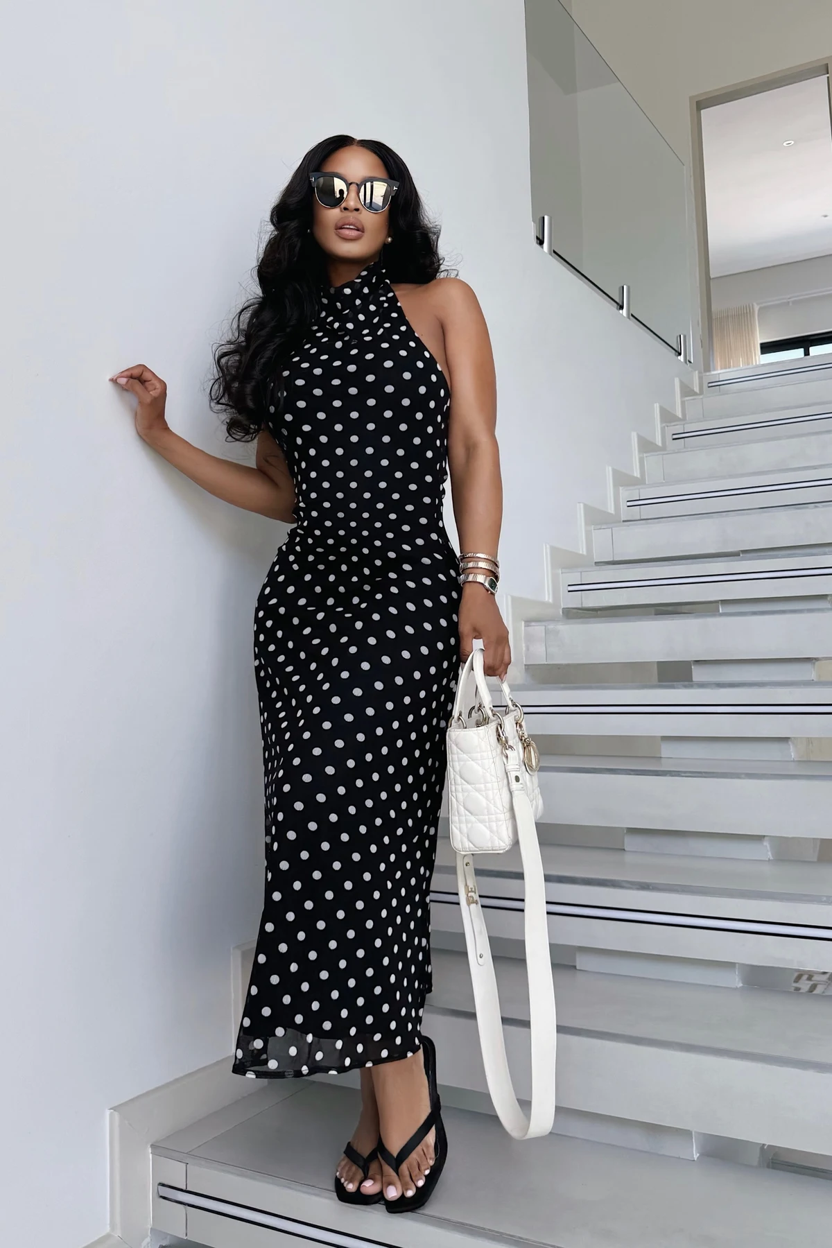 Woman in black polka-dot halter maxi dress on a staircase at Christmas