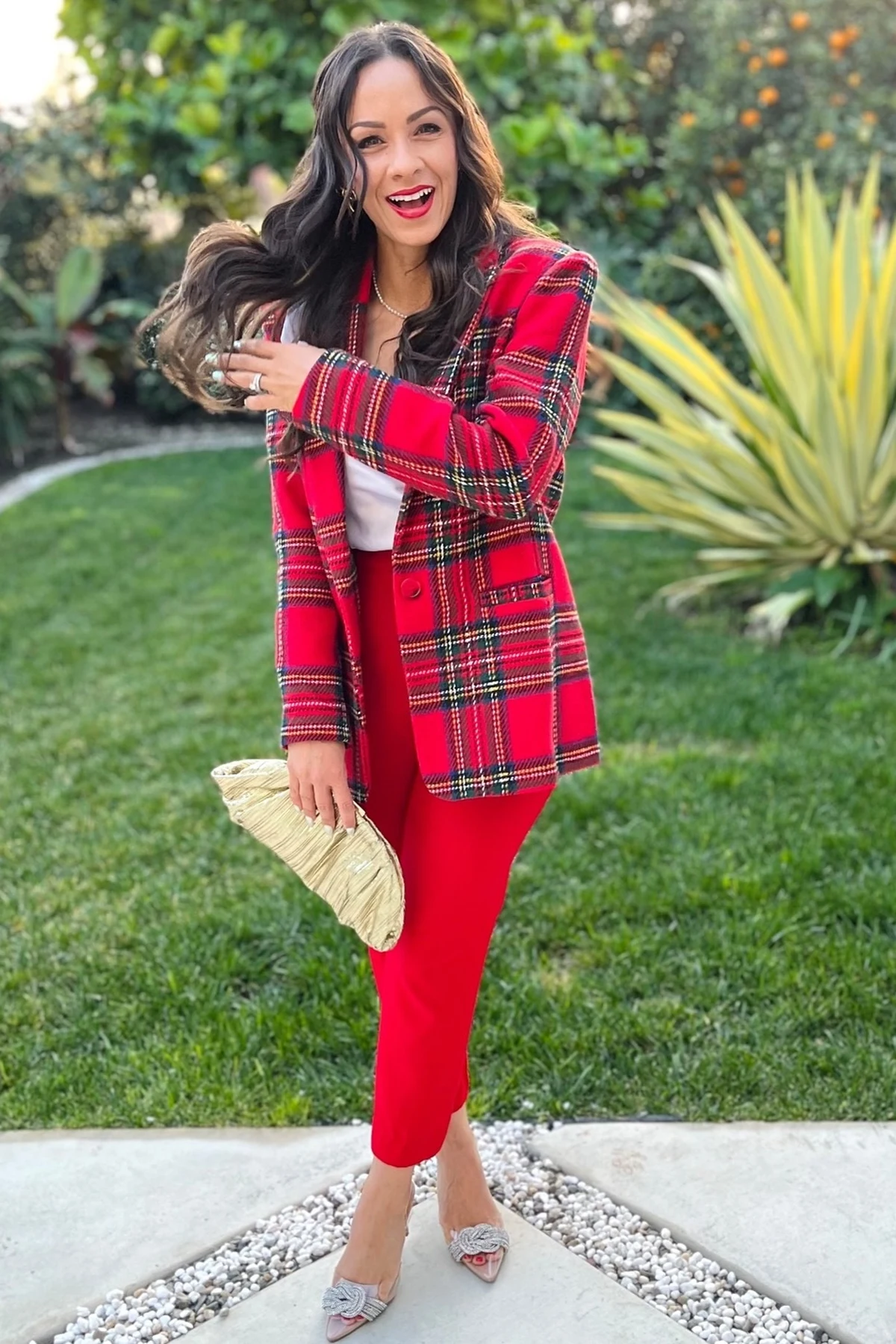 Woman in red tartan blazer and red trousers in a garden at Christmas