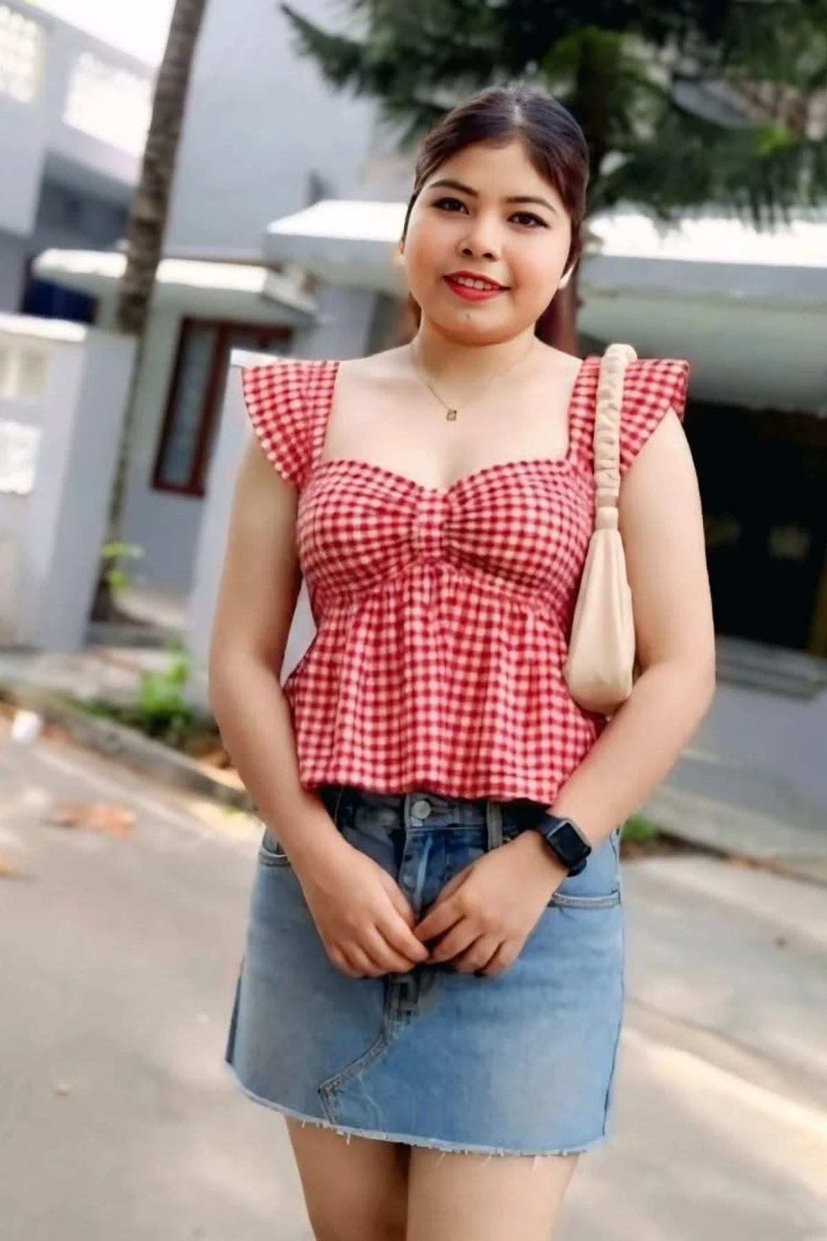 Woman in red gingham peplum top and denim skirt on a daytime street at Christmas