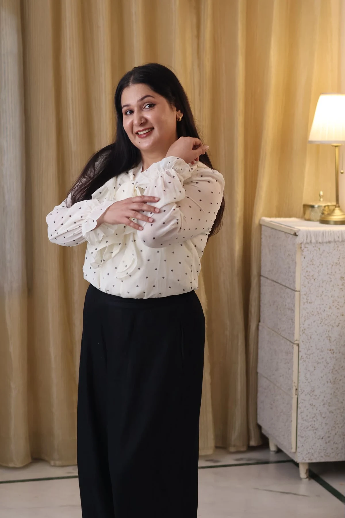 Woman in white polka-dot ruffle blouse and black wide-leg trousers at Christmas