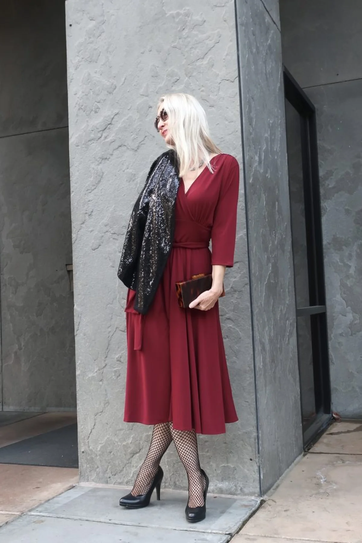 Woman in crimson wrap midi dress with sequin jacket and black heels