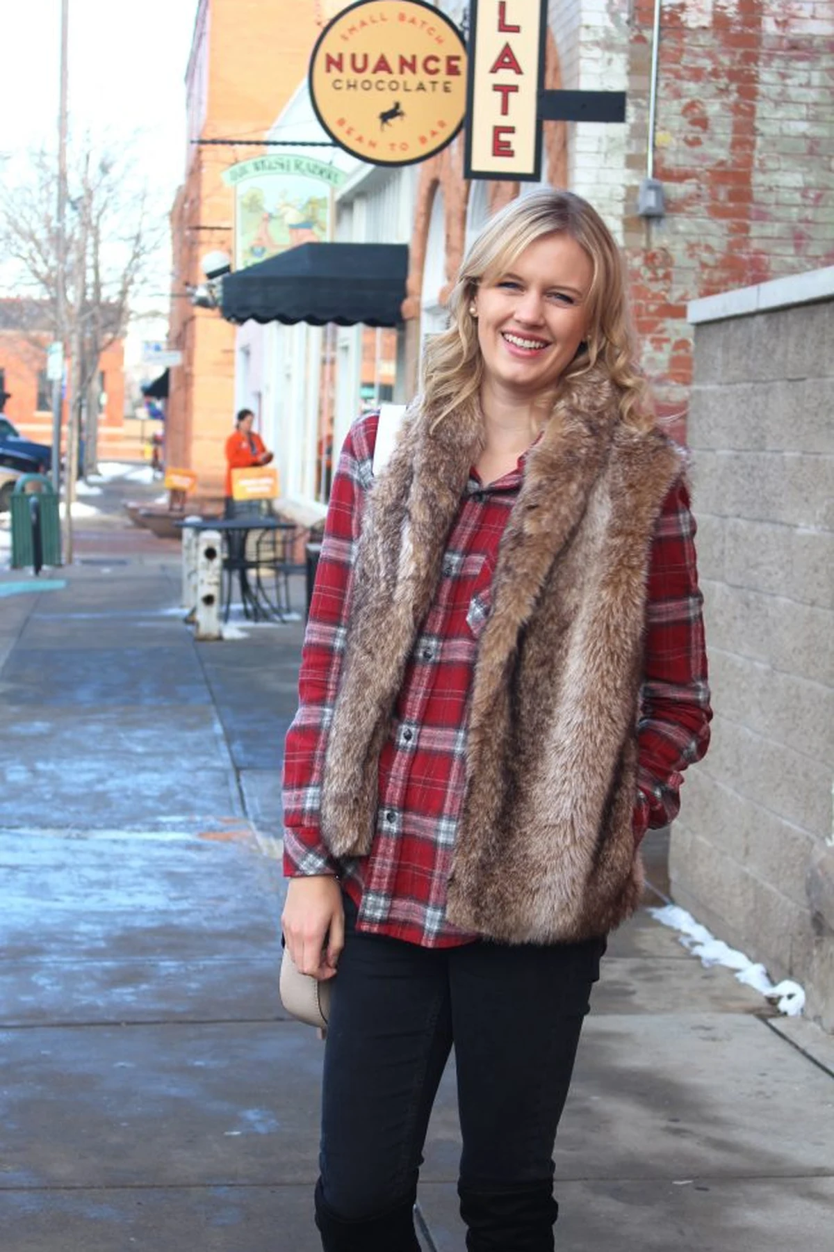 Woman in red plaid shirt and faux-fur vest with over-the-knee boots at Christmas
