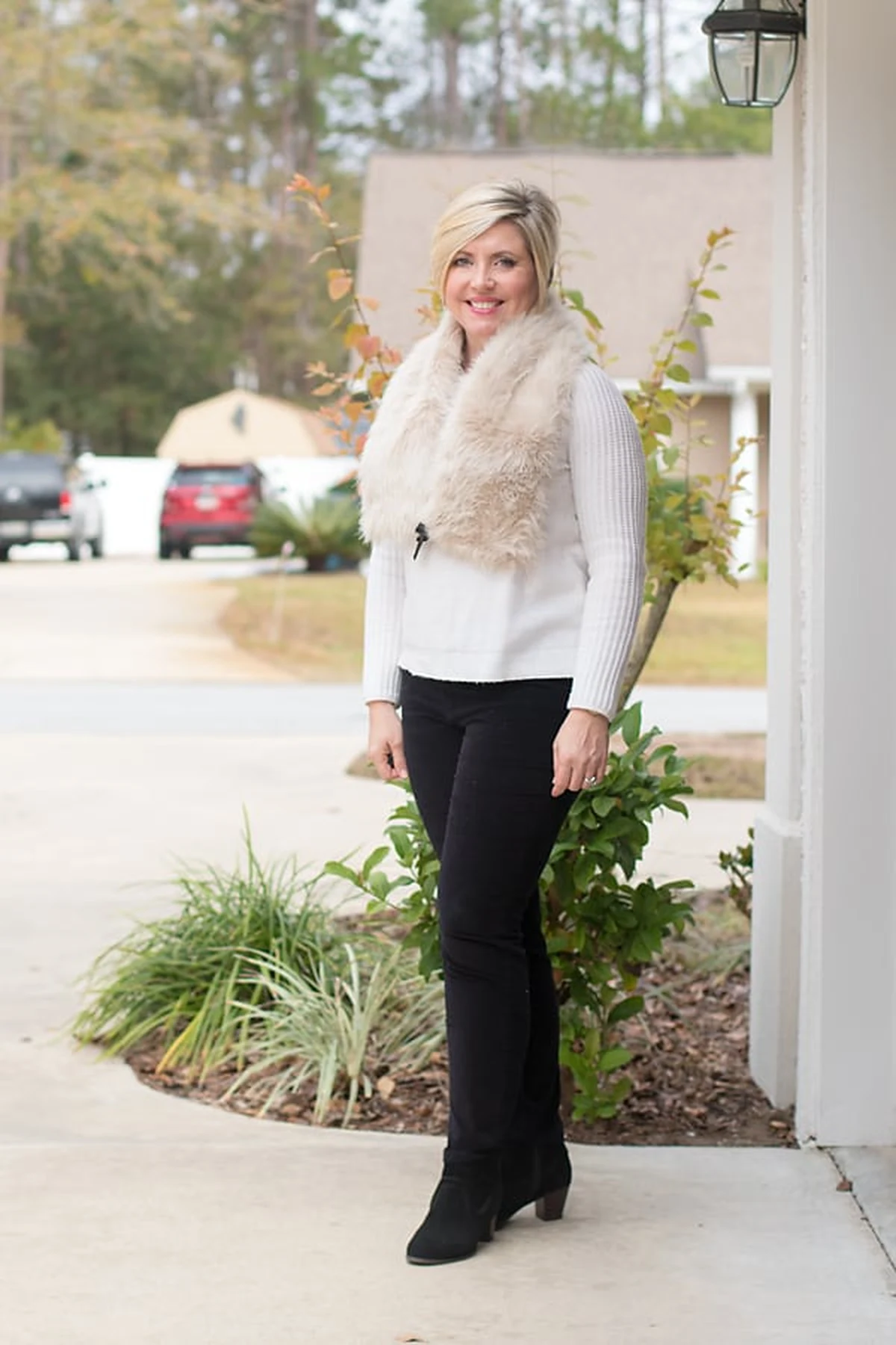 Woman in white sweater and faux-fur stole with black jeans at Christmas