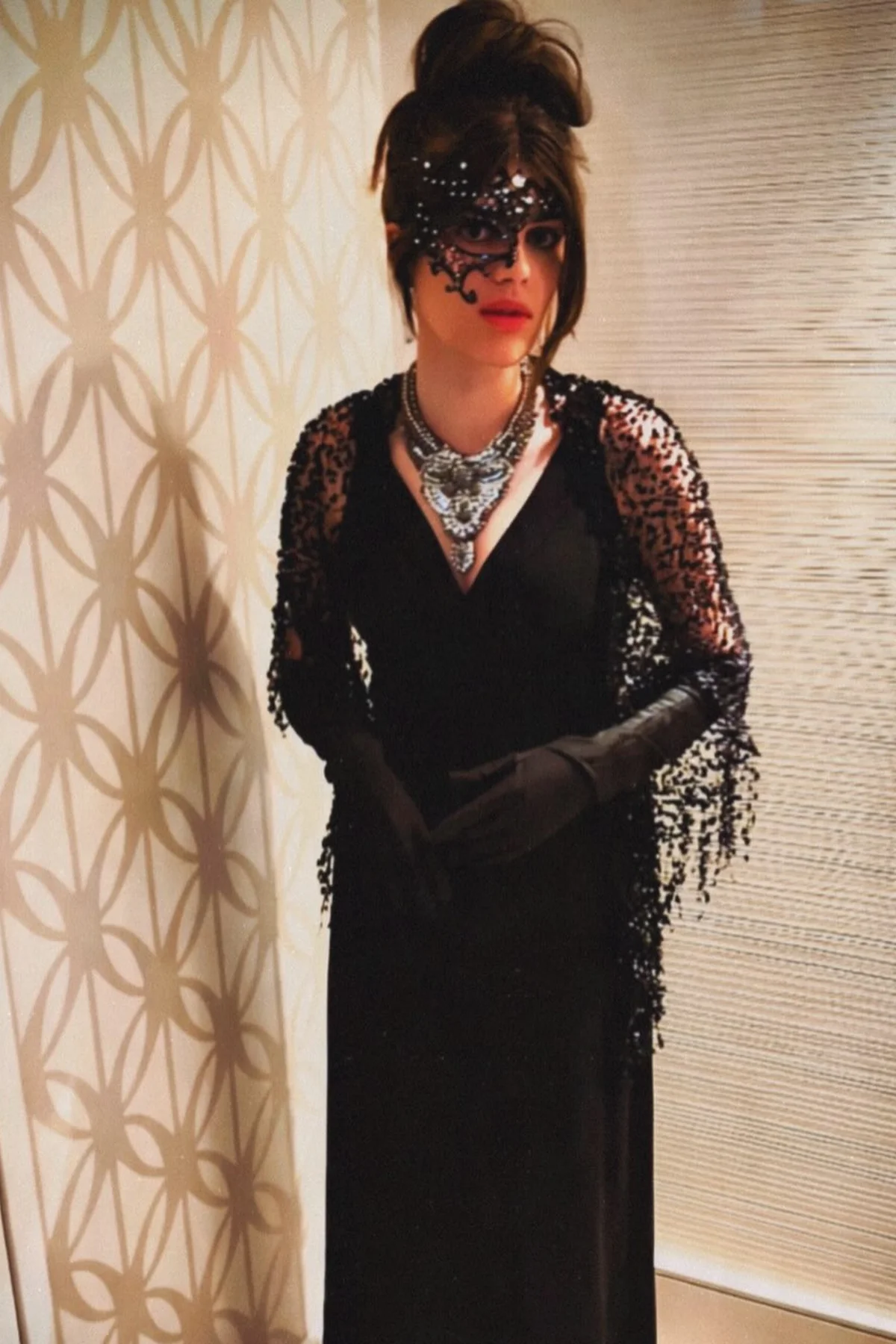 Woman in a black lace masquerade mask and black lace-sleeve maxi dress with long gloves, a midnight masquerade gothic Halloween costume