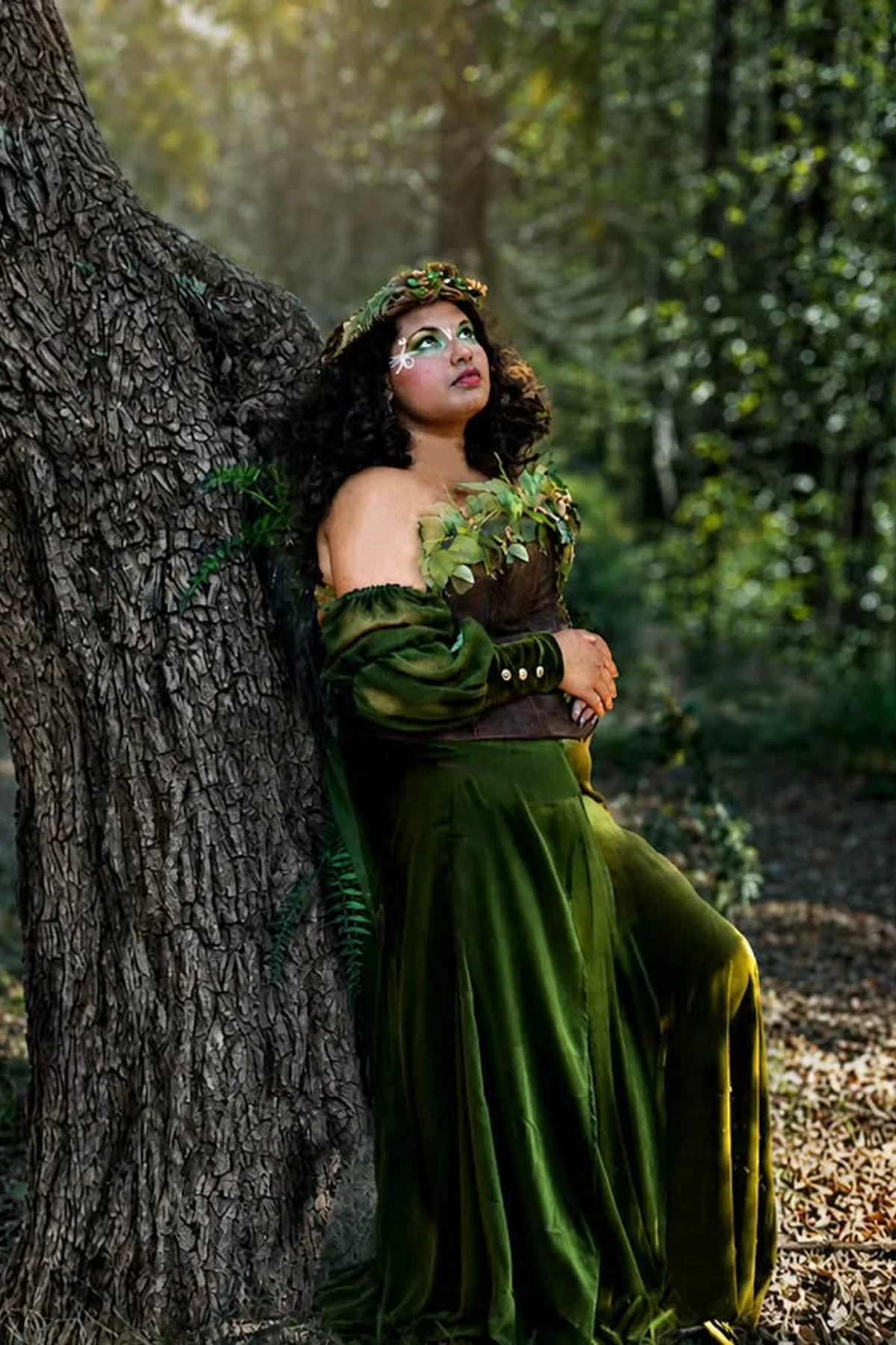 Plus size woman in a forest green velvet skirt and corset bodice with a leaf crown, a dark forest enchantress gothic Halloween costume