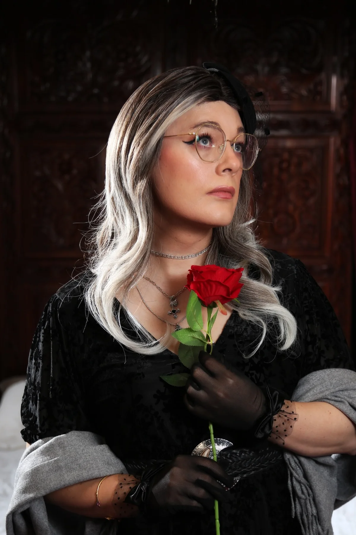 Woman in a black velvet dress with a gray shawl and red rose, a ghost widow gothic Halloween costume