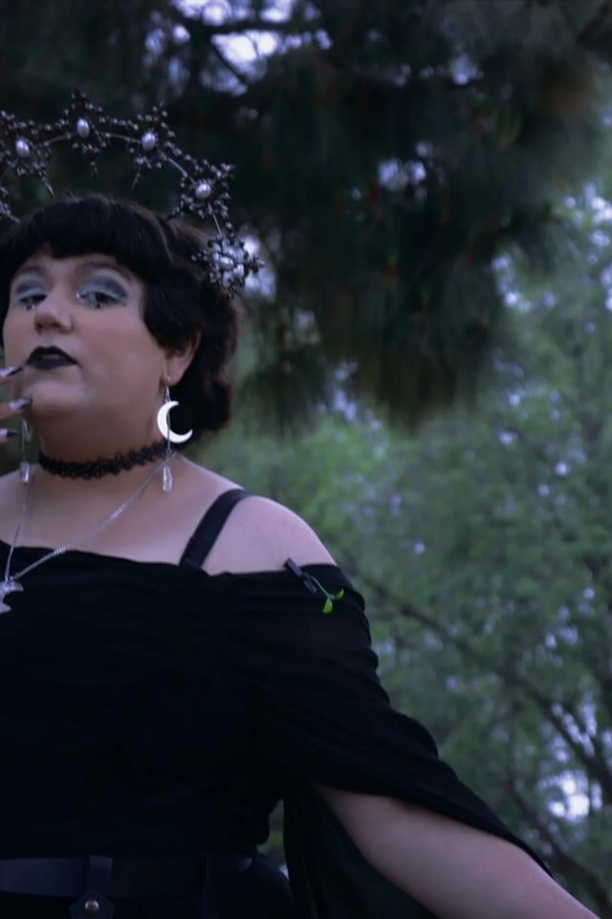 Plus size woman in a black off-shoulder top with moon jewelry and pearl crown, a moon priestess gothic Halloween costume