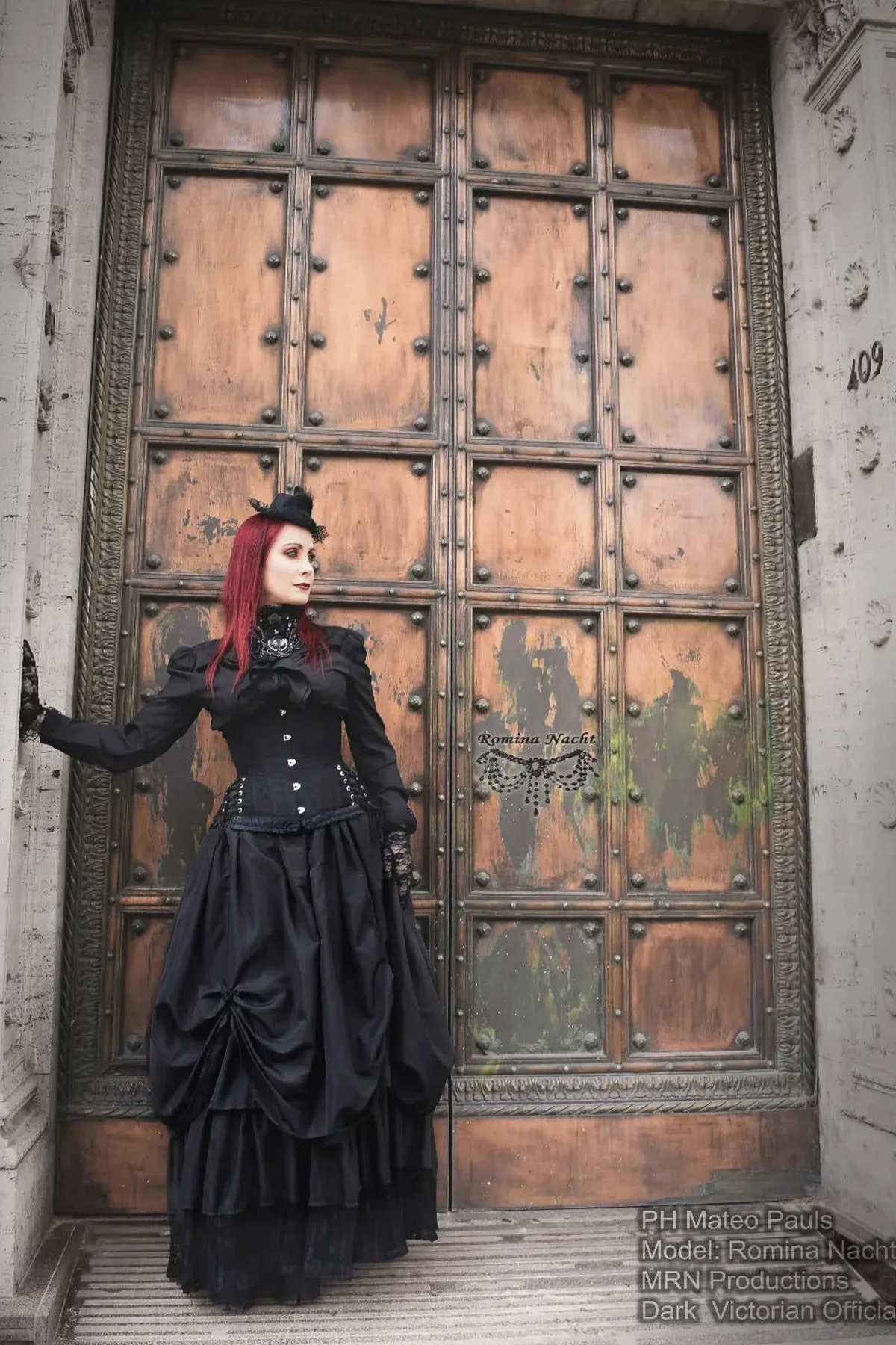 Woman in a black Victorian gown with corseted waist and lace fingerless gloves, a gothic vampire court lady Halloween costume