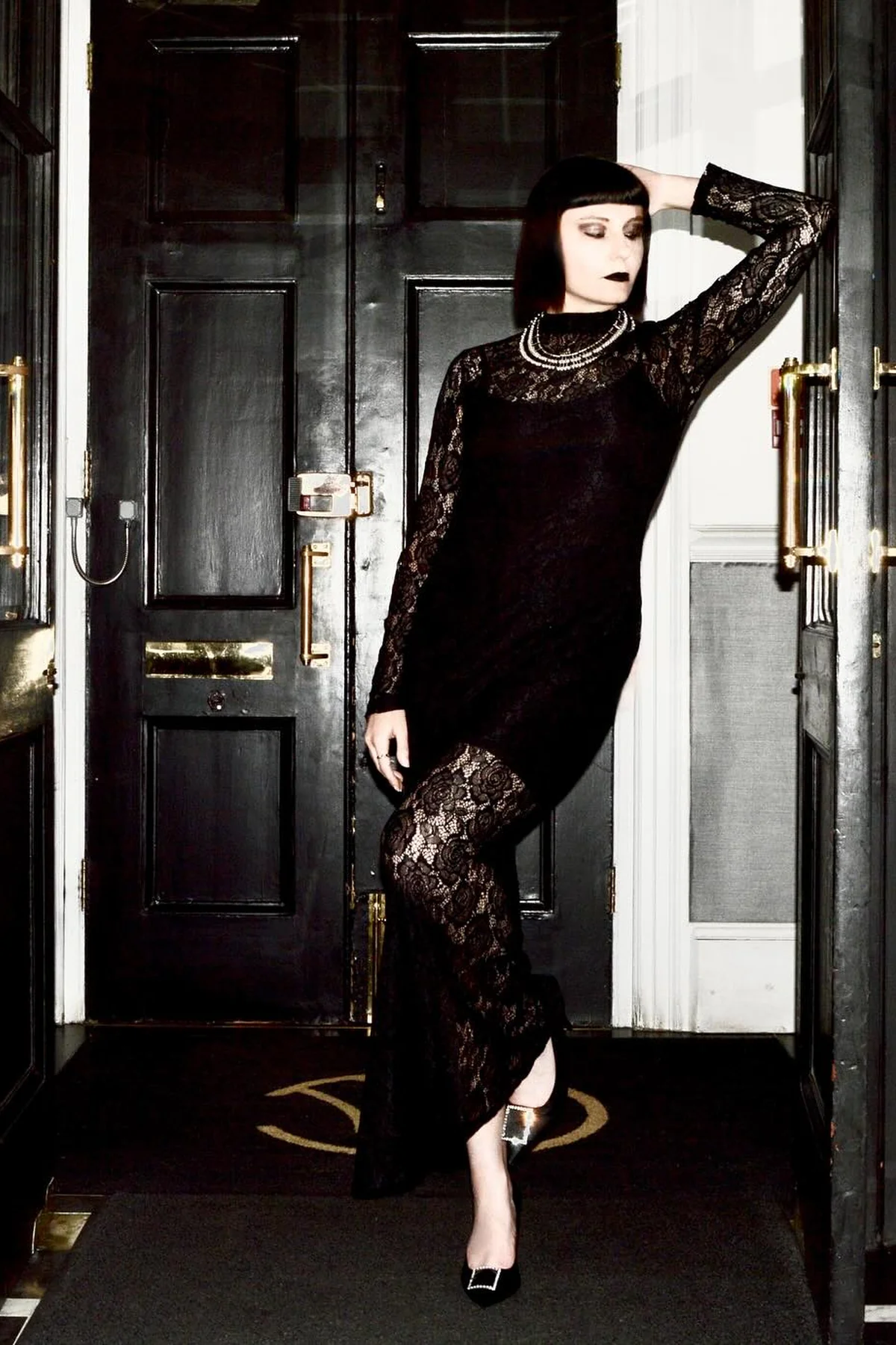 Woman in a black floral lace maxi dress with sheer lace sleeves, an elegant gothic garden witch Halloween costume