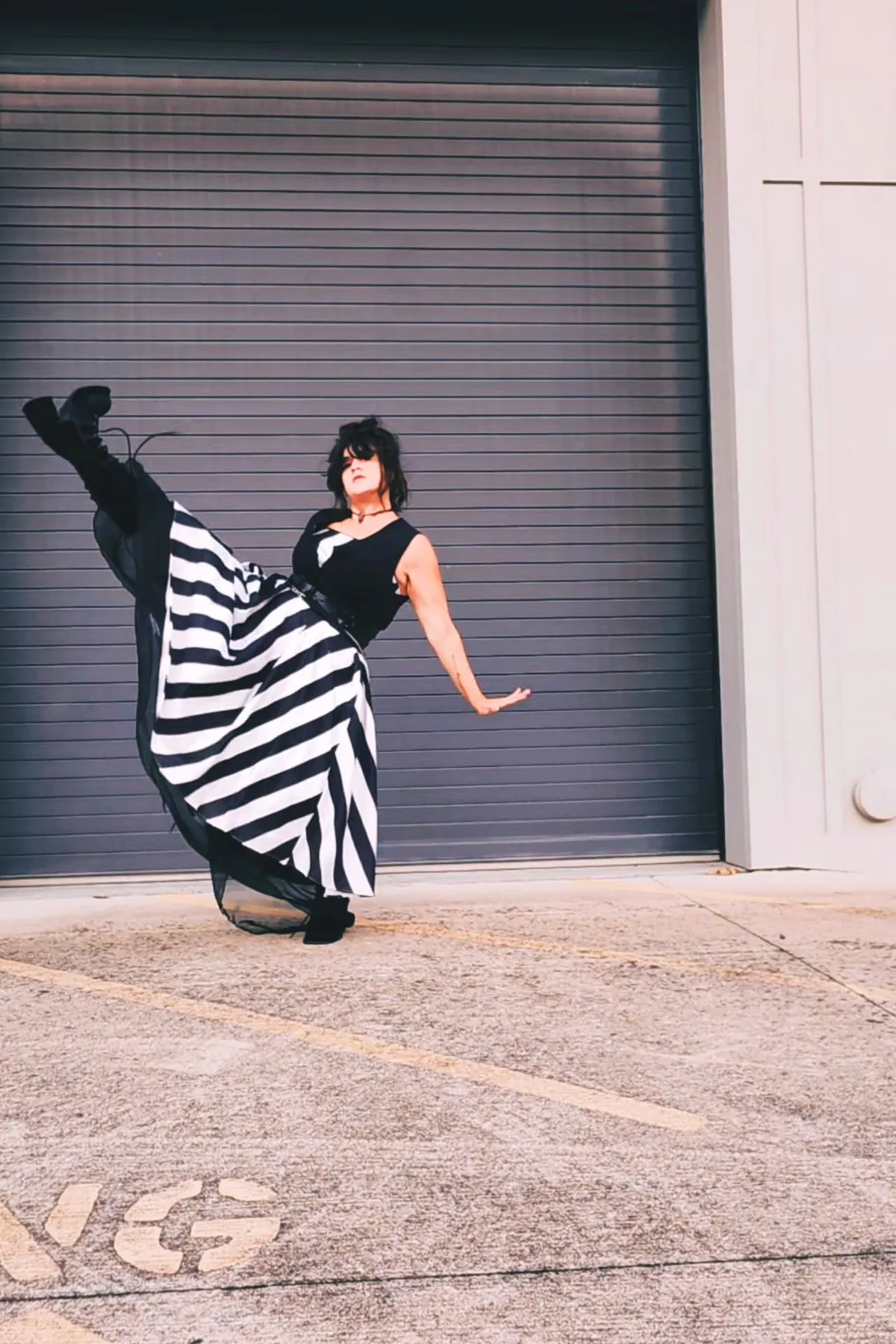 Woman in a striped top and cropped trousers, a quirky gothic Halloween costume over 50