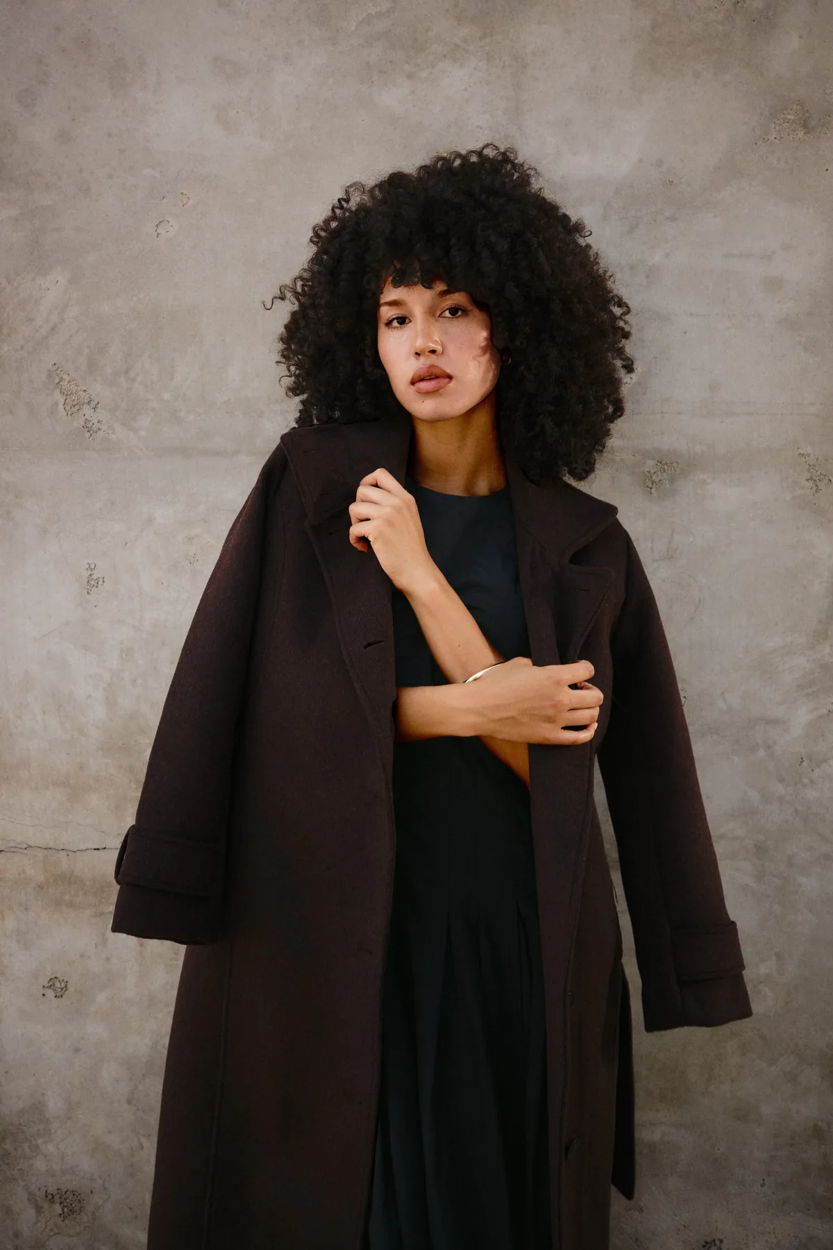 Woman in a chocolate brown coat and black dress, a refined gothic Halloween outfit