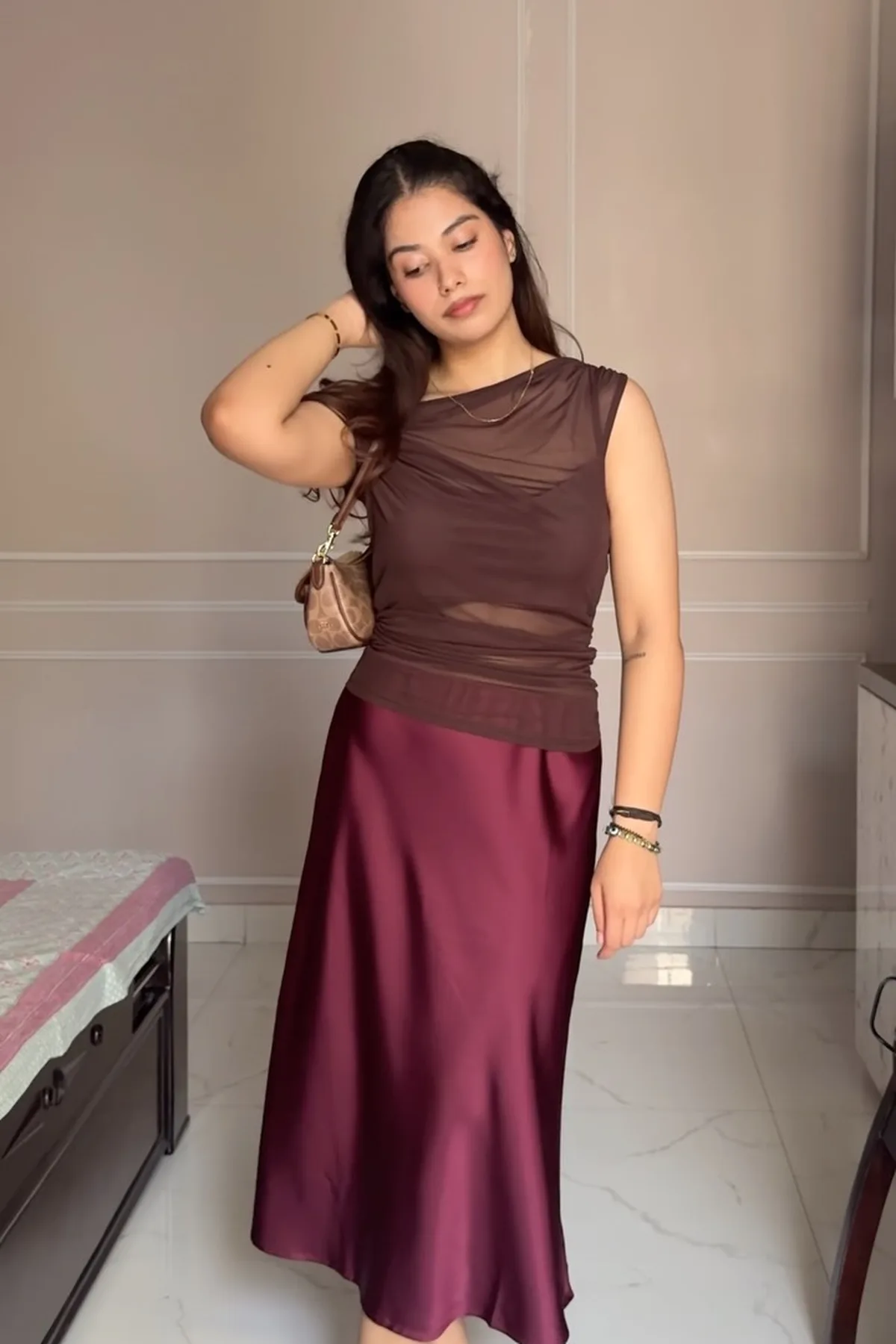 Woman in a plum satin skirt and mesh-sleeve top, a dressy gothic Halloween outfit over 50