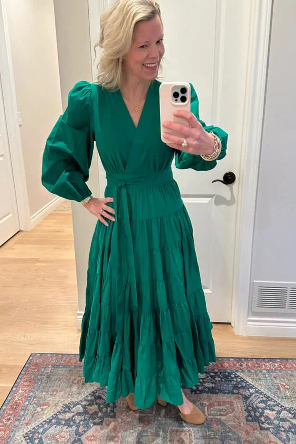 Woman in an emerald green puff-sleeve tiered maxi dress with a self-tie belt