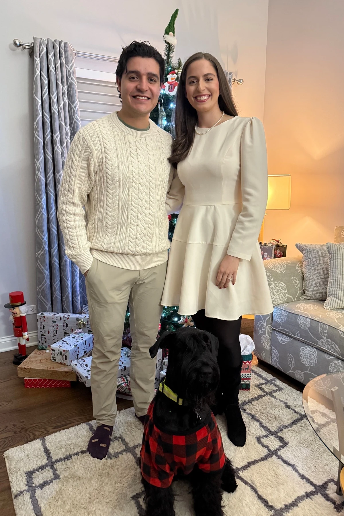 Woman in a winter-white long-sleeve fit-and-flare dress with black tights by a Christmas tree