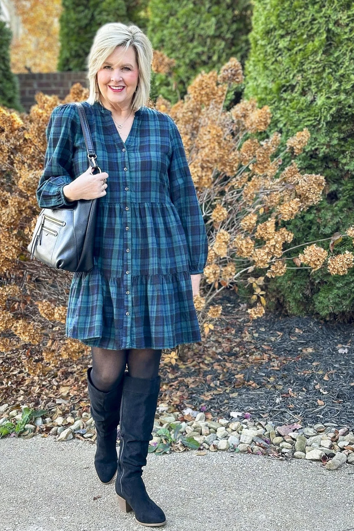 Woman in a blue-green tartan tiered shirtdress with long puff sleeves and tall boots